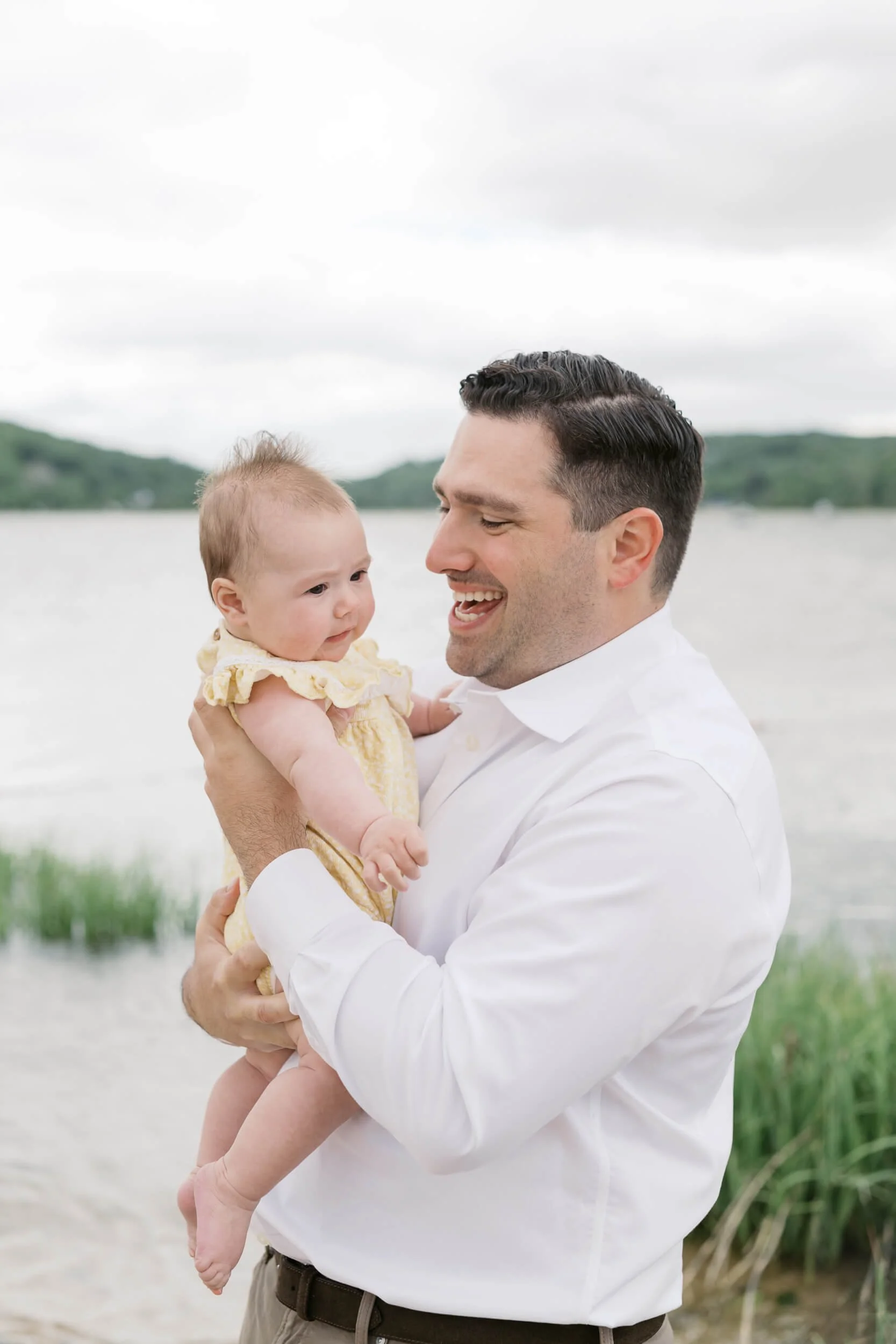 Dad holding baby girl on beach photos