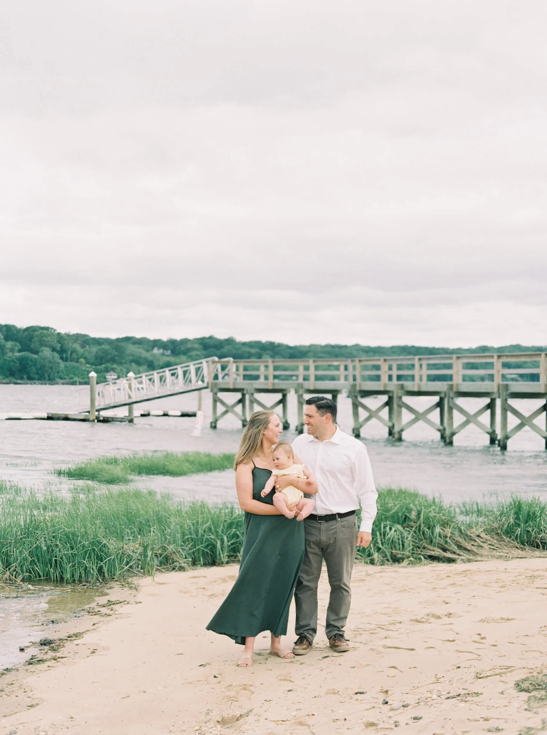 New Parents walking on the beach with baby girl
