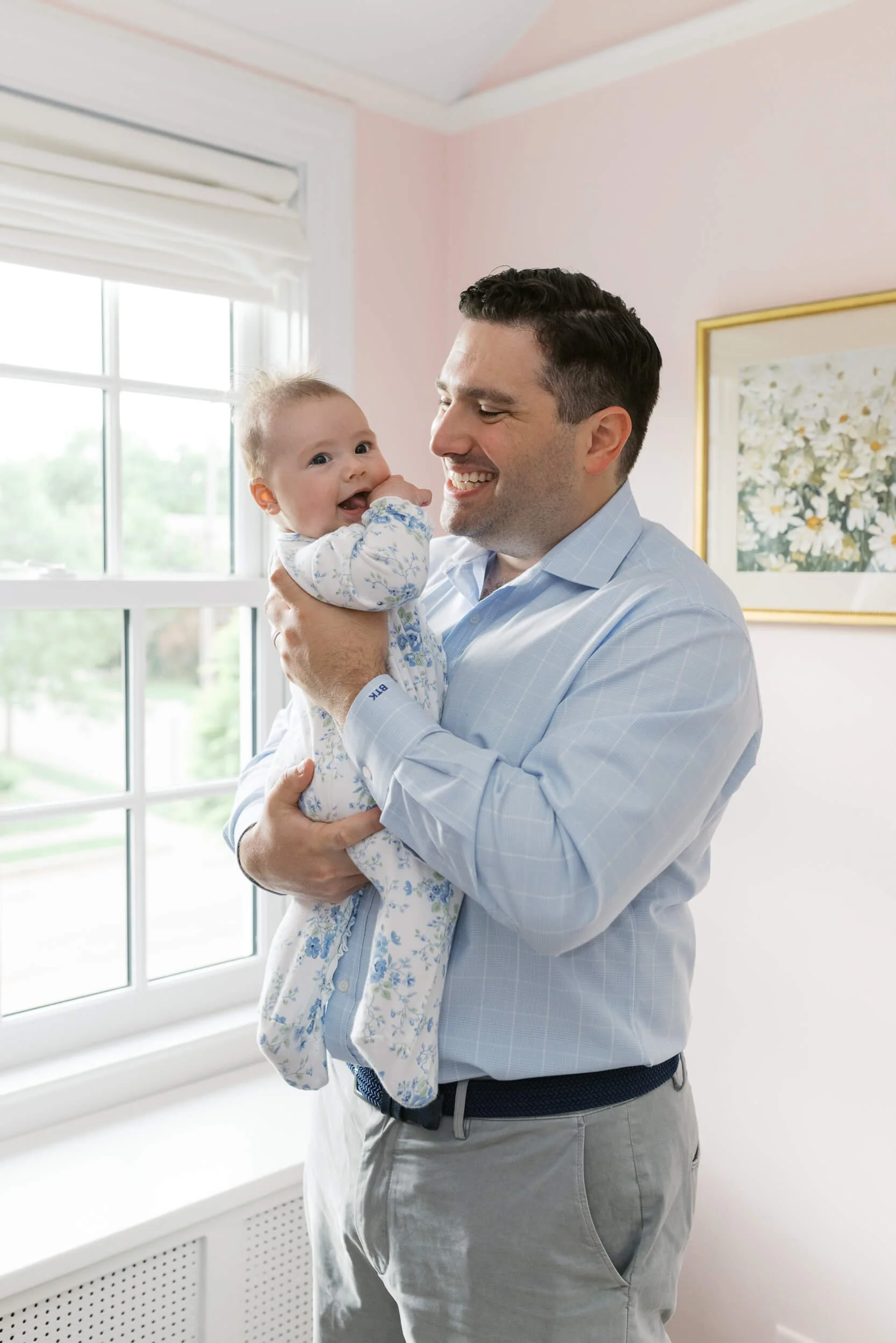 Dad holds his daughter close while mom looks on, captured during a Cold Spring Harbor family photography session.