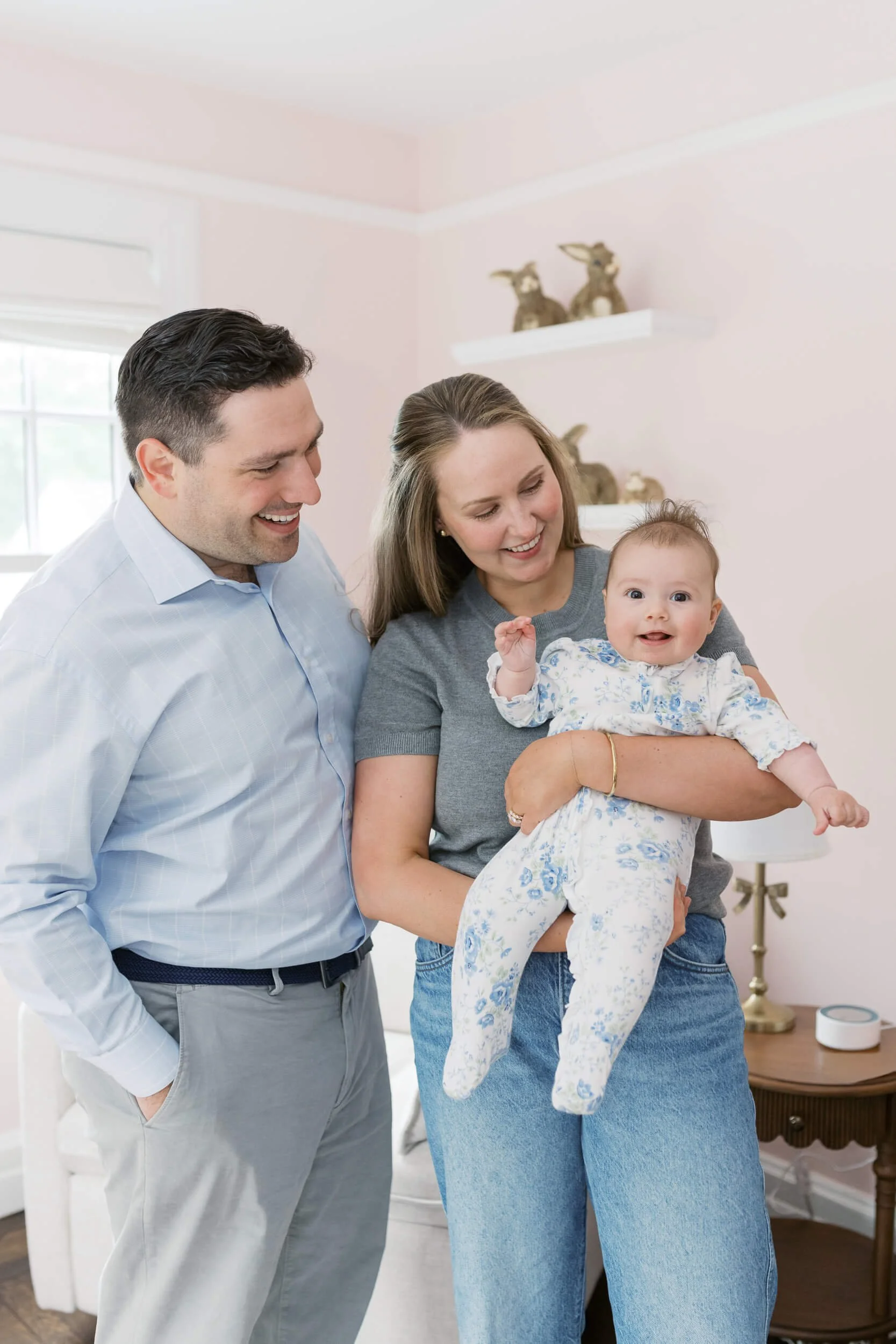 Parents and their daughter sit together in natural light for milestone family photos in Cold Spring Harbor, NY.