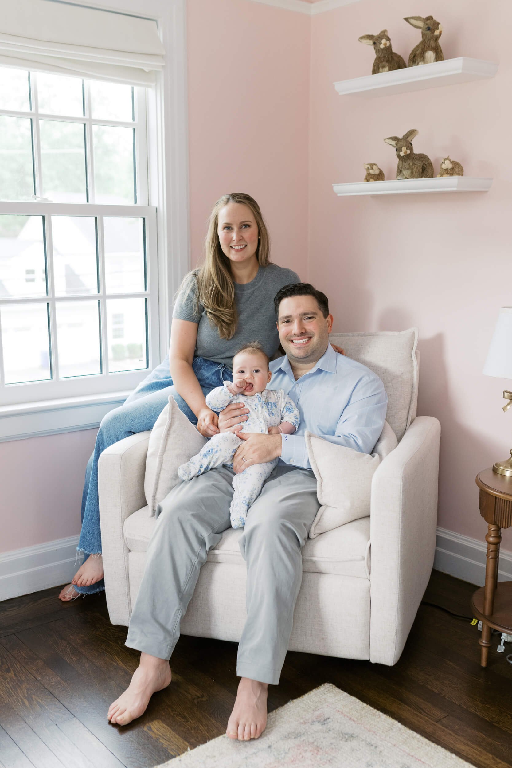 Parents and their daughter sit together in natural light for milestone family photos in Cold Spring Harbor, NY.