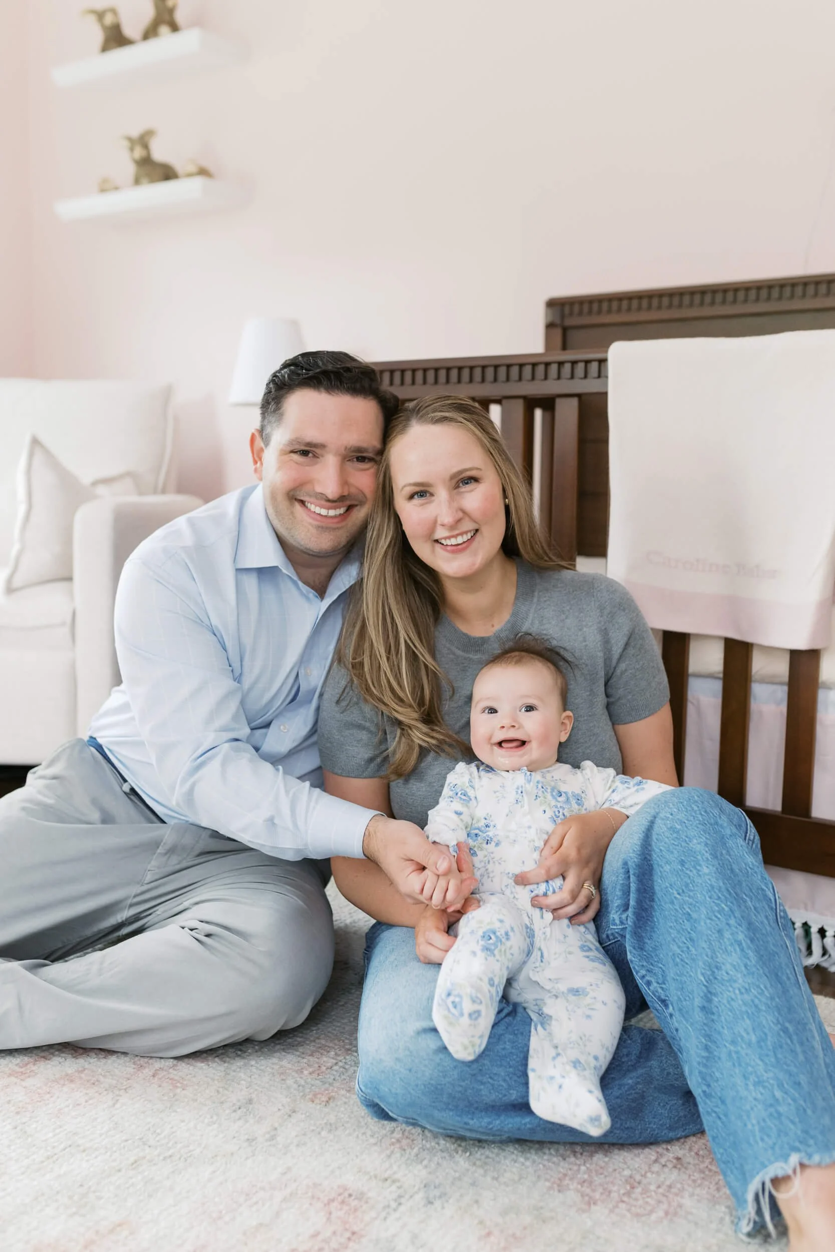Mom and dad sit together on the nursery floor for their daughter's six-month milestone session.