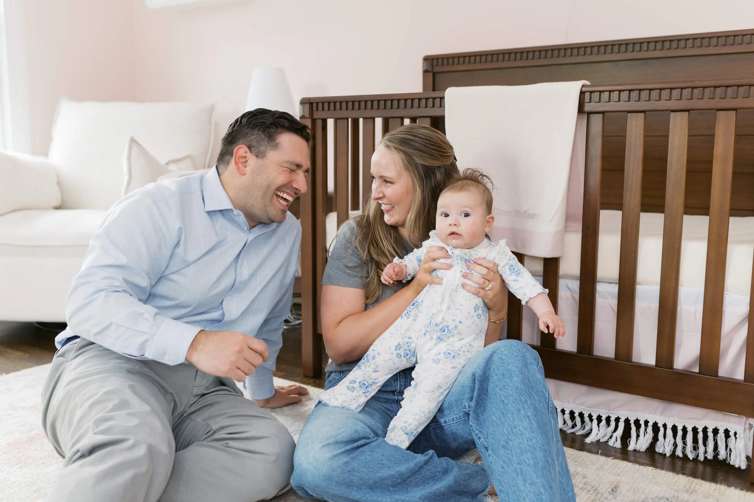 Mom and dad sit together on the nursery floor for their daughter's six-month milestone session.
