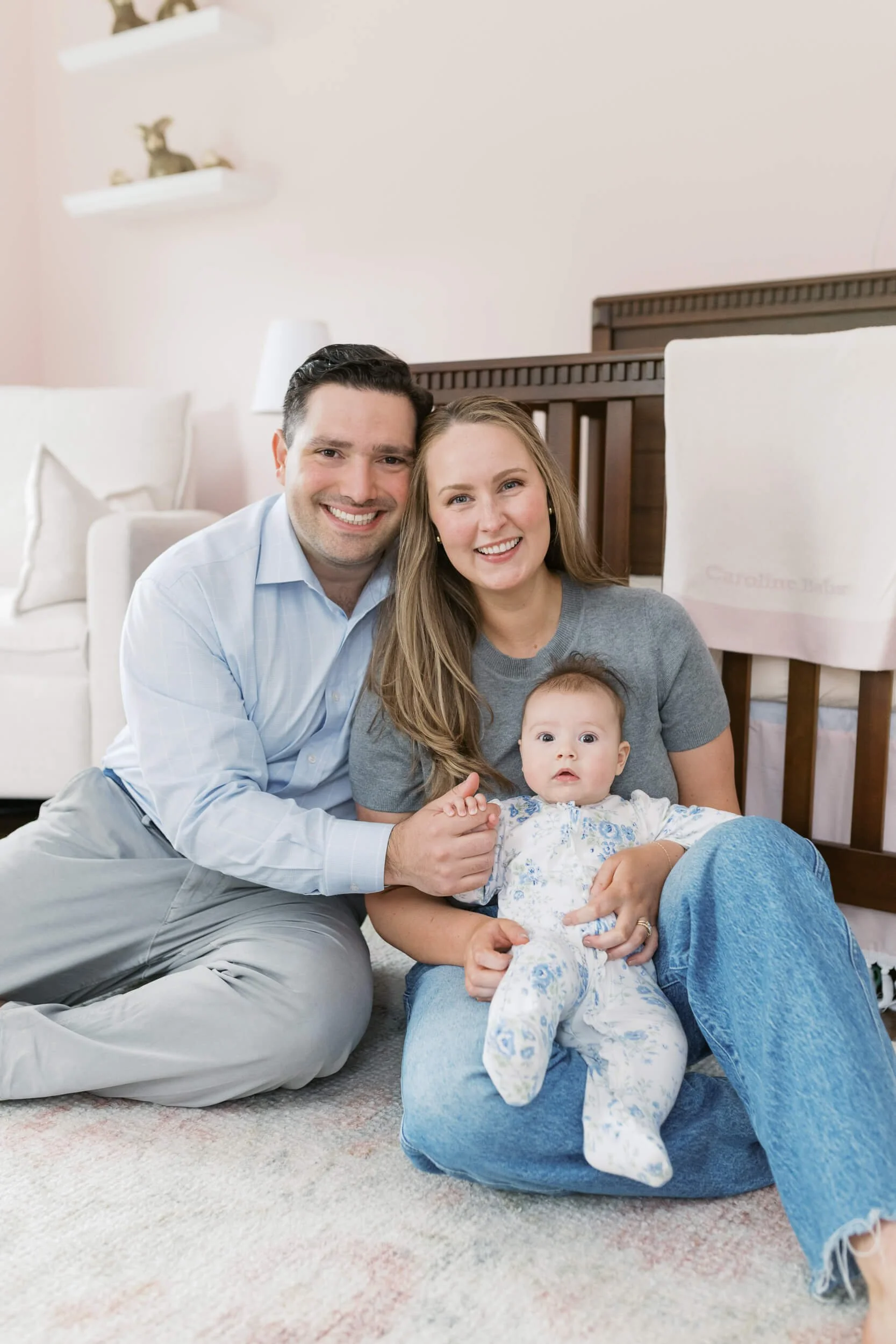 Mom and dad sit together on the nursery floor for their daughter's six-month milestone session.