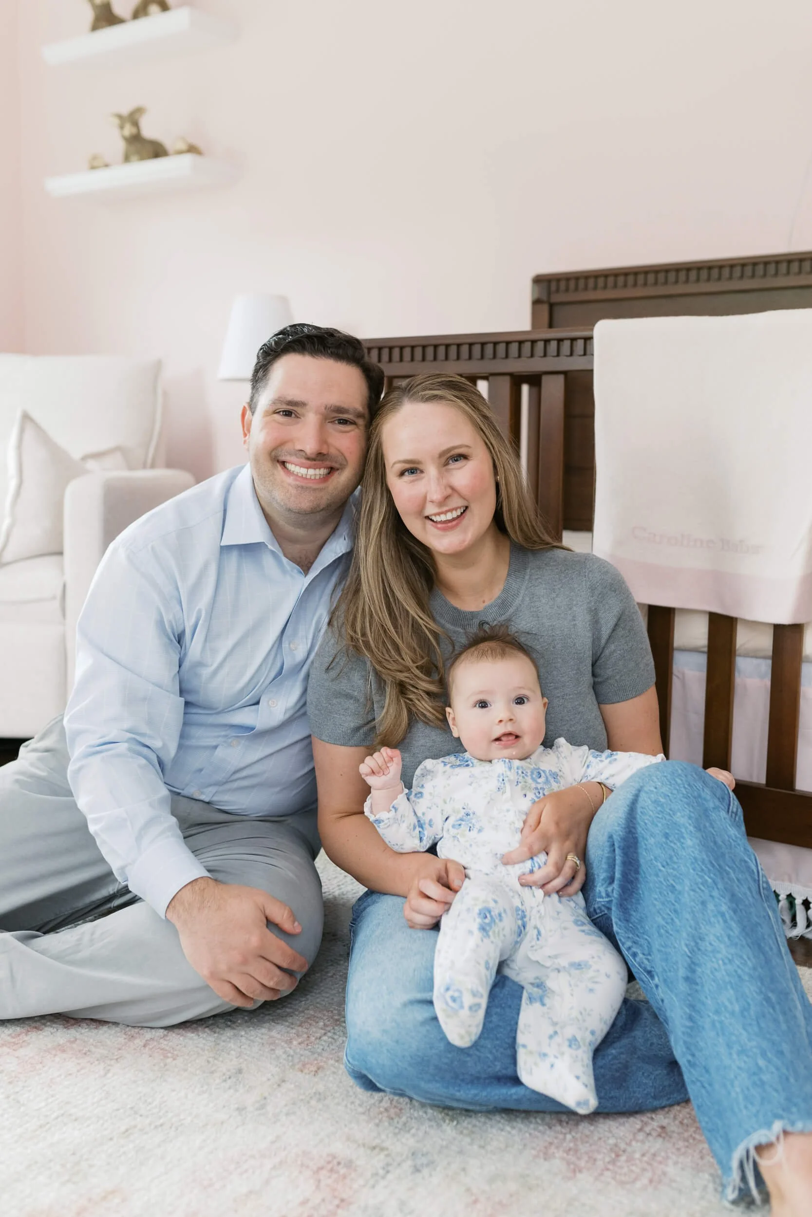 Parents and their daughter sit together in natural light for milestone family photos in Cold Spring Harbor, NY.