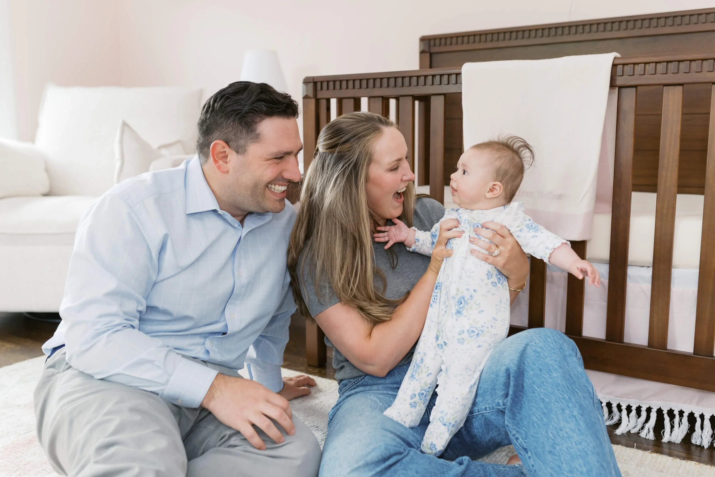 Mom and dad sit together on the nursery floor for their daughter's six-month milestone session.