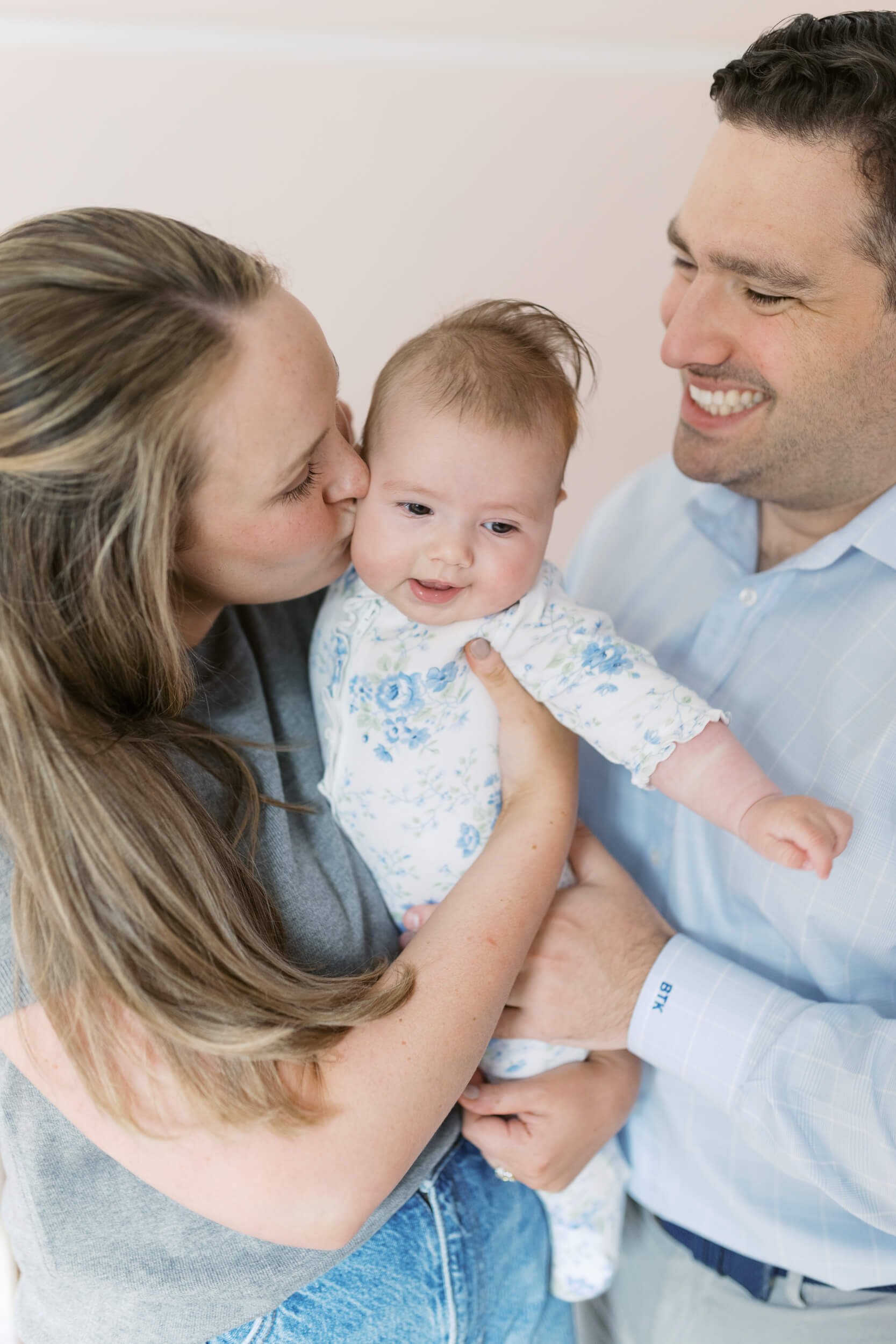 Parents and their daughter sit together in natural light for milestone family photos in Cold Spring Harbor, NY.