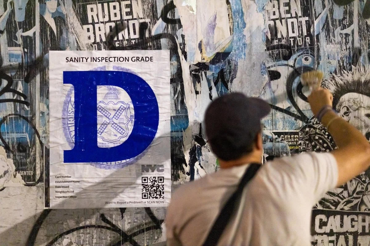 Joe Bertino applying wheat paste posters to a wall