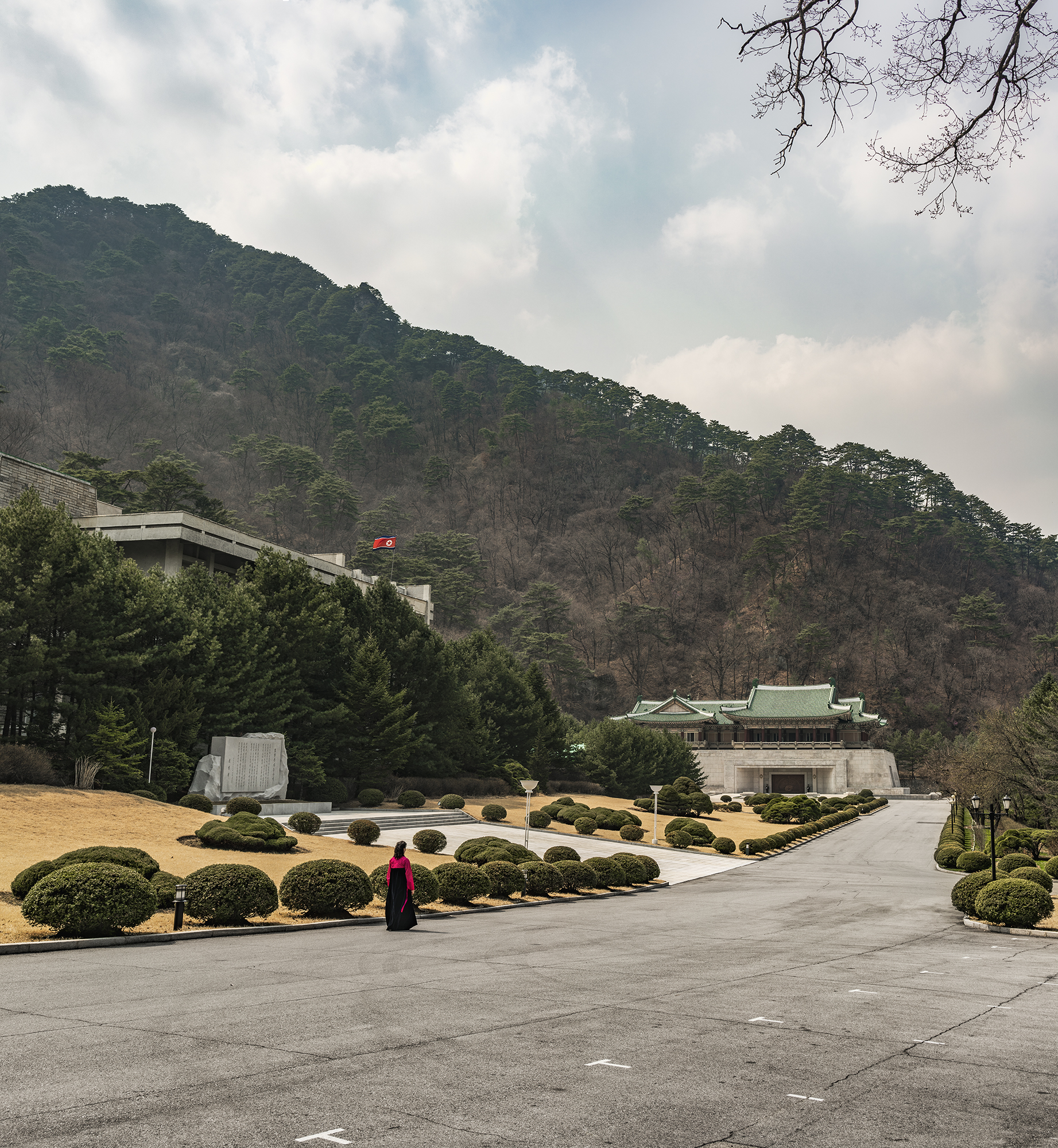 A North Korean guide wearing a traditional dress is walking towards the International Friendship Exhibition Hall in the Myohyang Mountains area. The complex is an underground exhibition consisting of all the gifts that the Great and Dear Leaders o