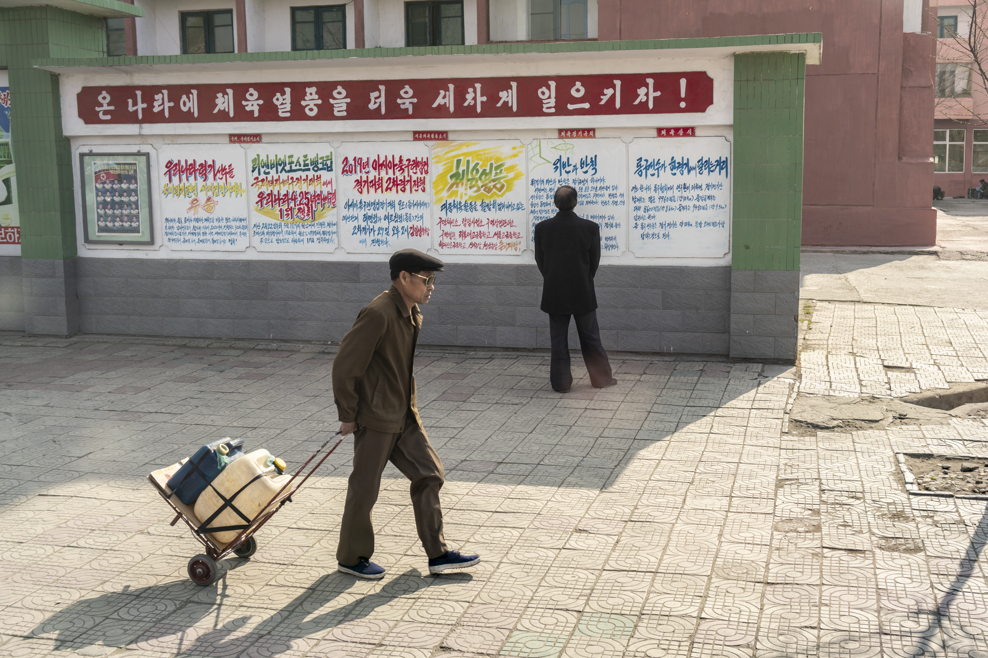  A man is reading propaganda messages on a wall in a Pyongyang neighbourhood.  All propaganda messages are produced following the guidelines set by the Propaganda and Agitation Department (PAD) and placed throughout the whole country to encourage peo