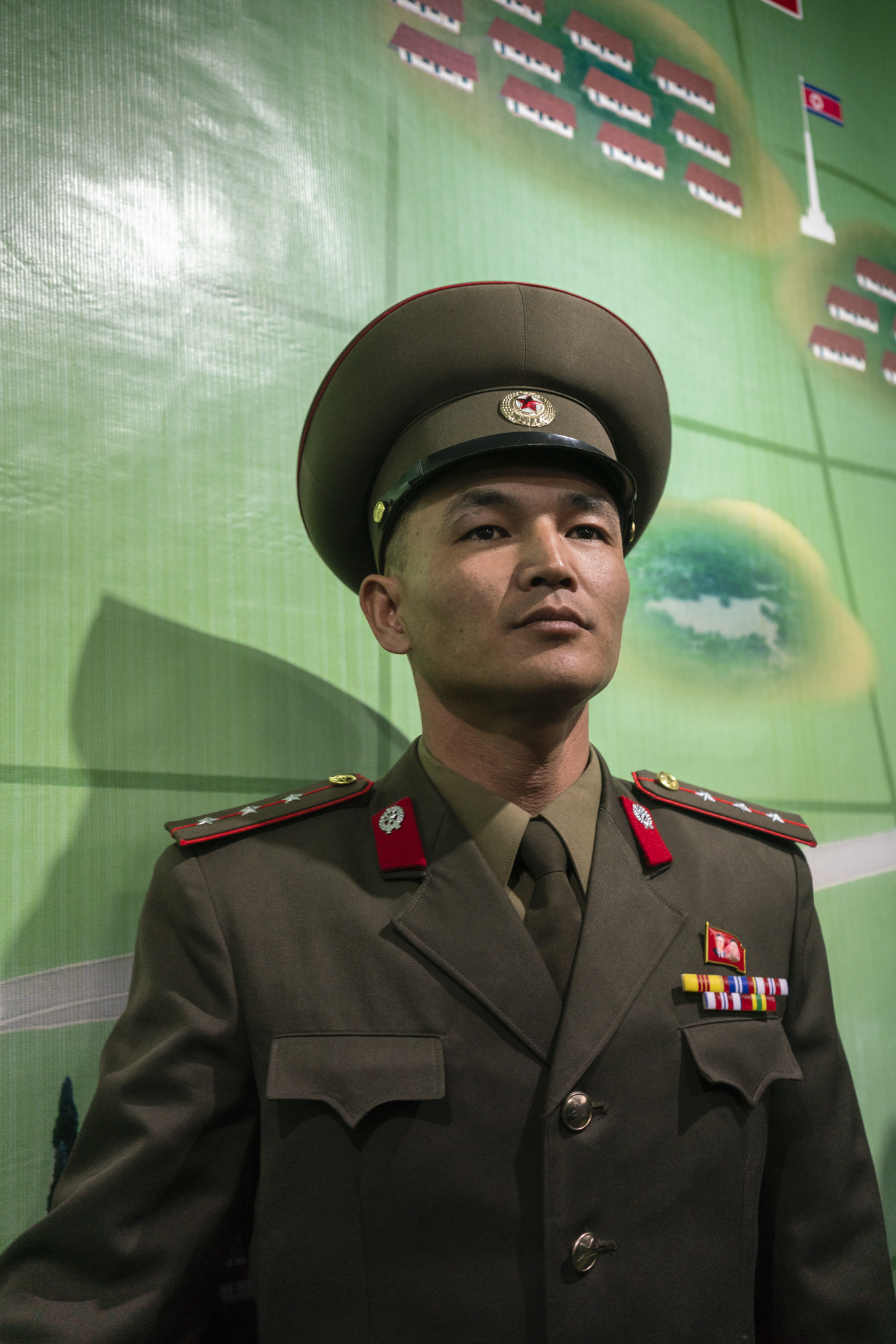 A North Korean official is standing in front of a map that illustrates the border between North and South Korea in the DMZ.