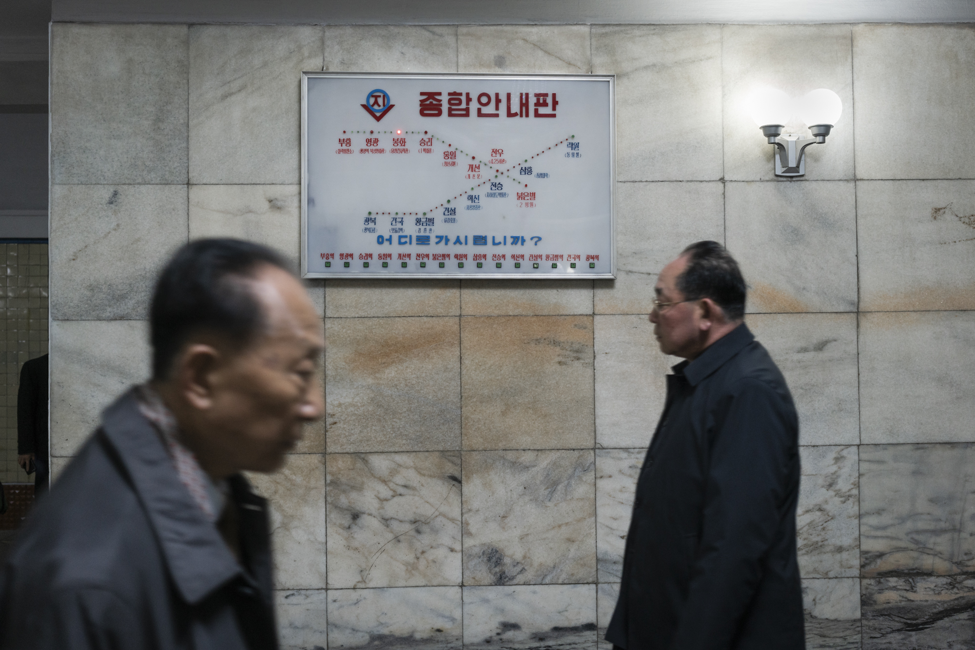 Commuters walking in front of an electronic board on the Chollima line at the Pyongyang metro Station.
