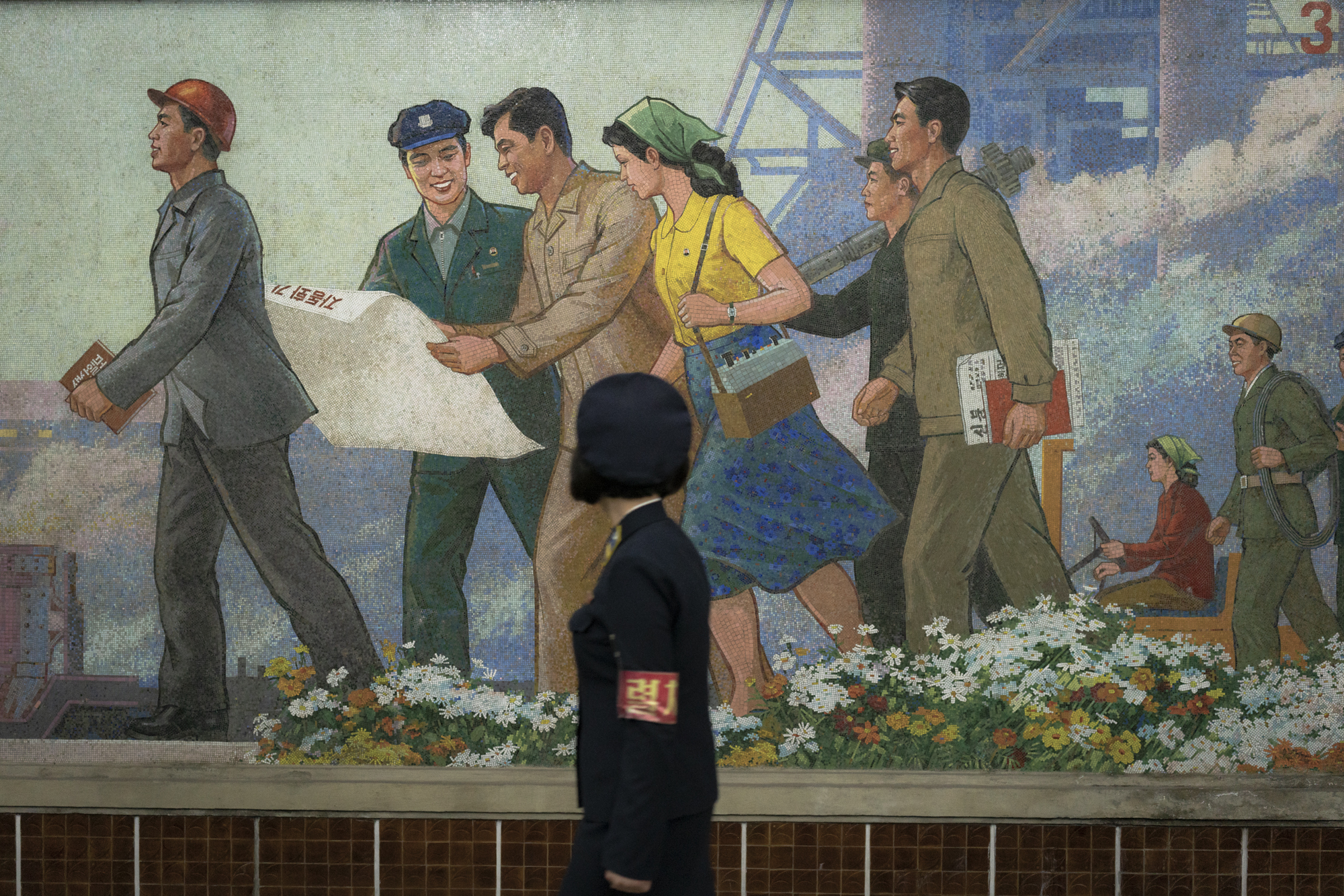 At Puhung (Prosperity) Station, built in 1987 and one of the many 100-metre deep subway stations on the Pyongyang subway network, a North Korean metro attendant is walking in front of one the many propaganda murals depicting revolutionary and social