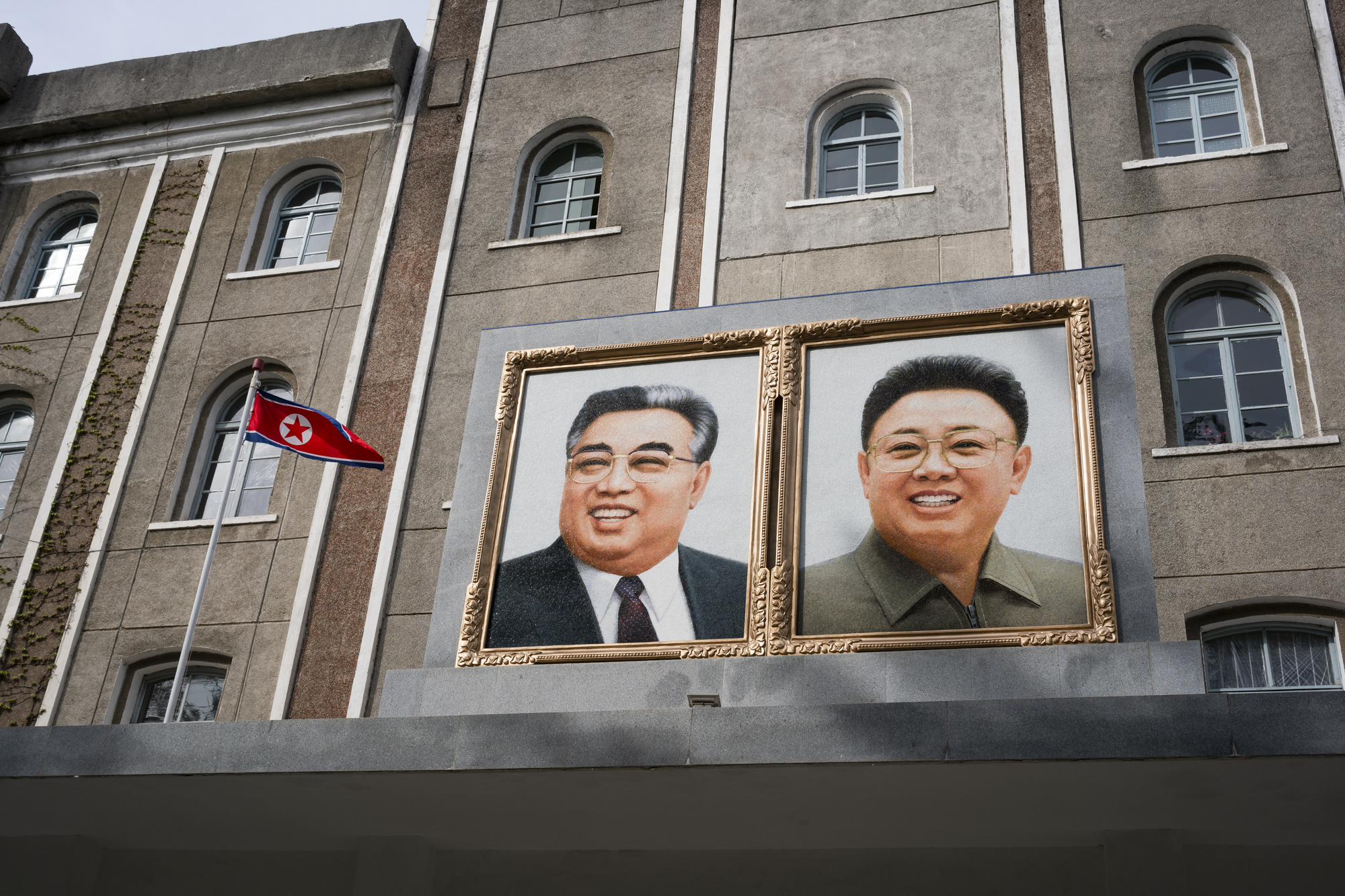  A DPRK flag and large-scale mosaics of the Great Leaders oversee the entrance of the Wŏnsan Agricultural University.  Founded in 1948 and built on the remains of an old German church, the university is a nonprofit and prestigious institution accredi