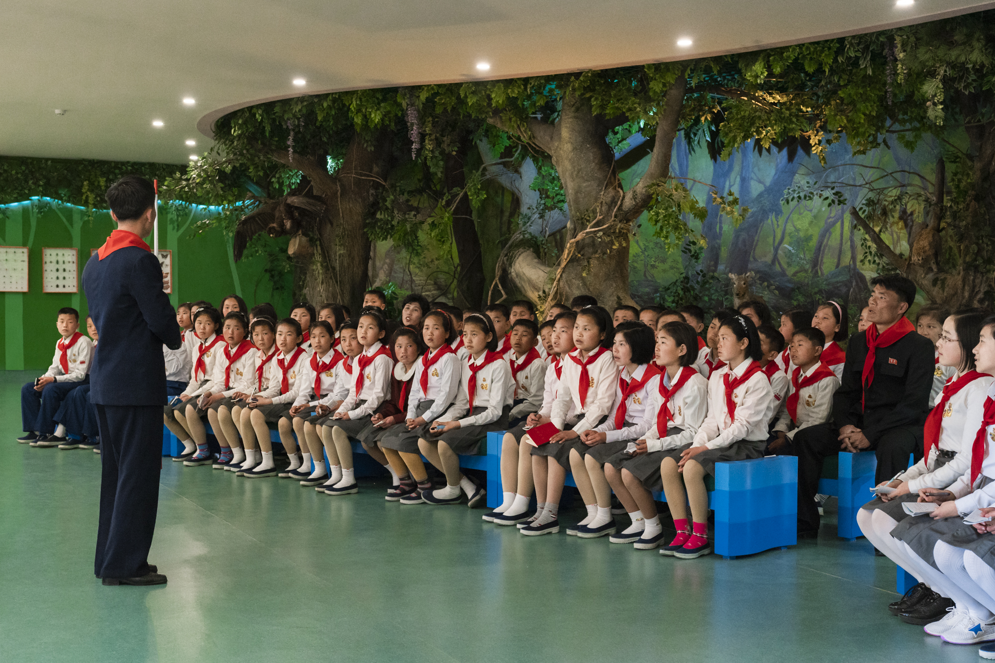  Students of the Songdowon International Children’s Camp are told by their teacher to revere the“Great Leader” Kim Il Sung.  The Political indoctrination starts at a young age in North Korea, where propaganda about the Eternal Leader and his  Juche  