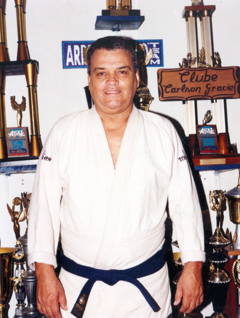 Carlson Gracie in his gi in front of his trophies