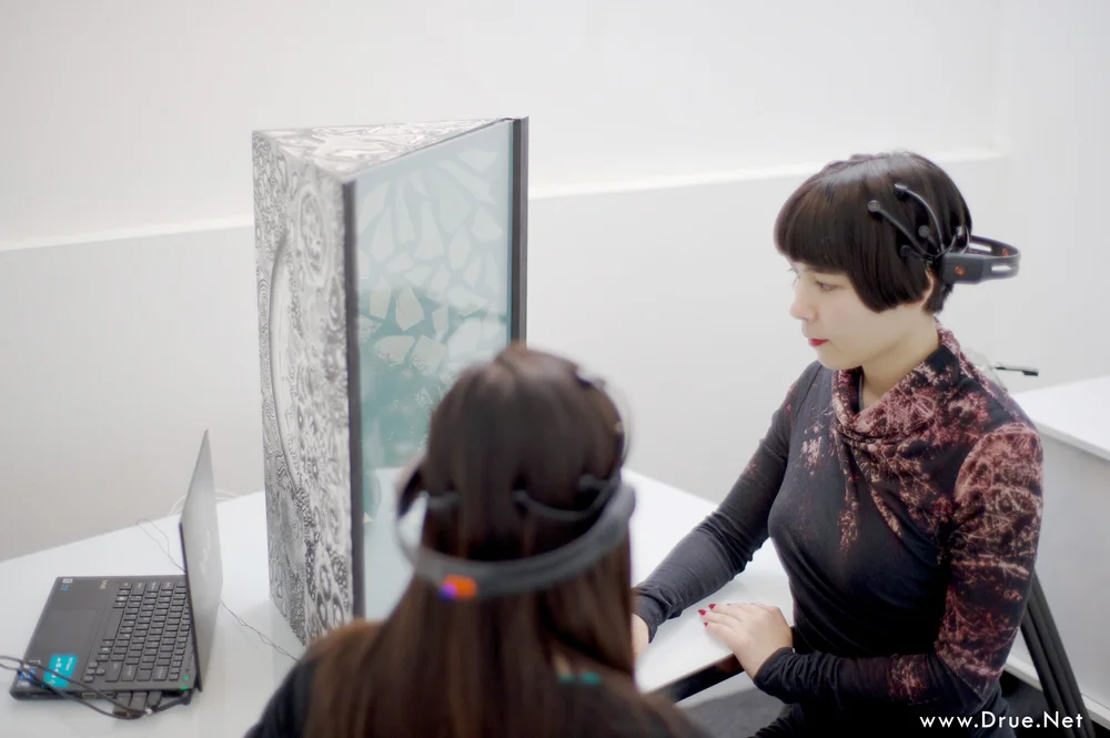 Kataoka and participant observing "Tree of pascal" as their brain waves are printed on the piece.