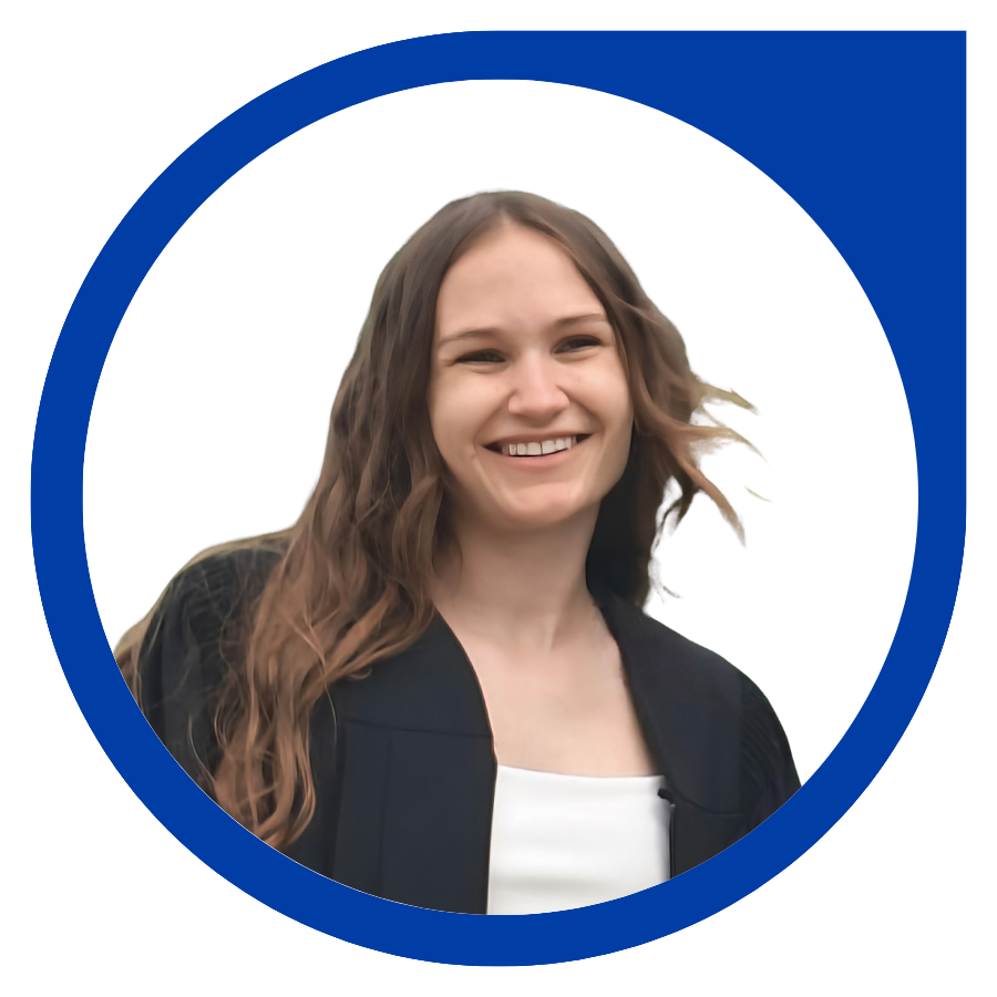 A young woman smiling with long brown hair, wearing a black graduation gown and a white top, against a white background with a blue circular border.
