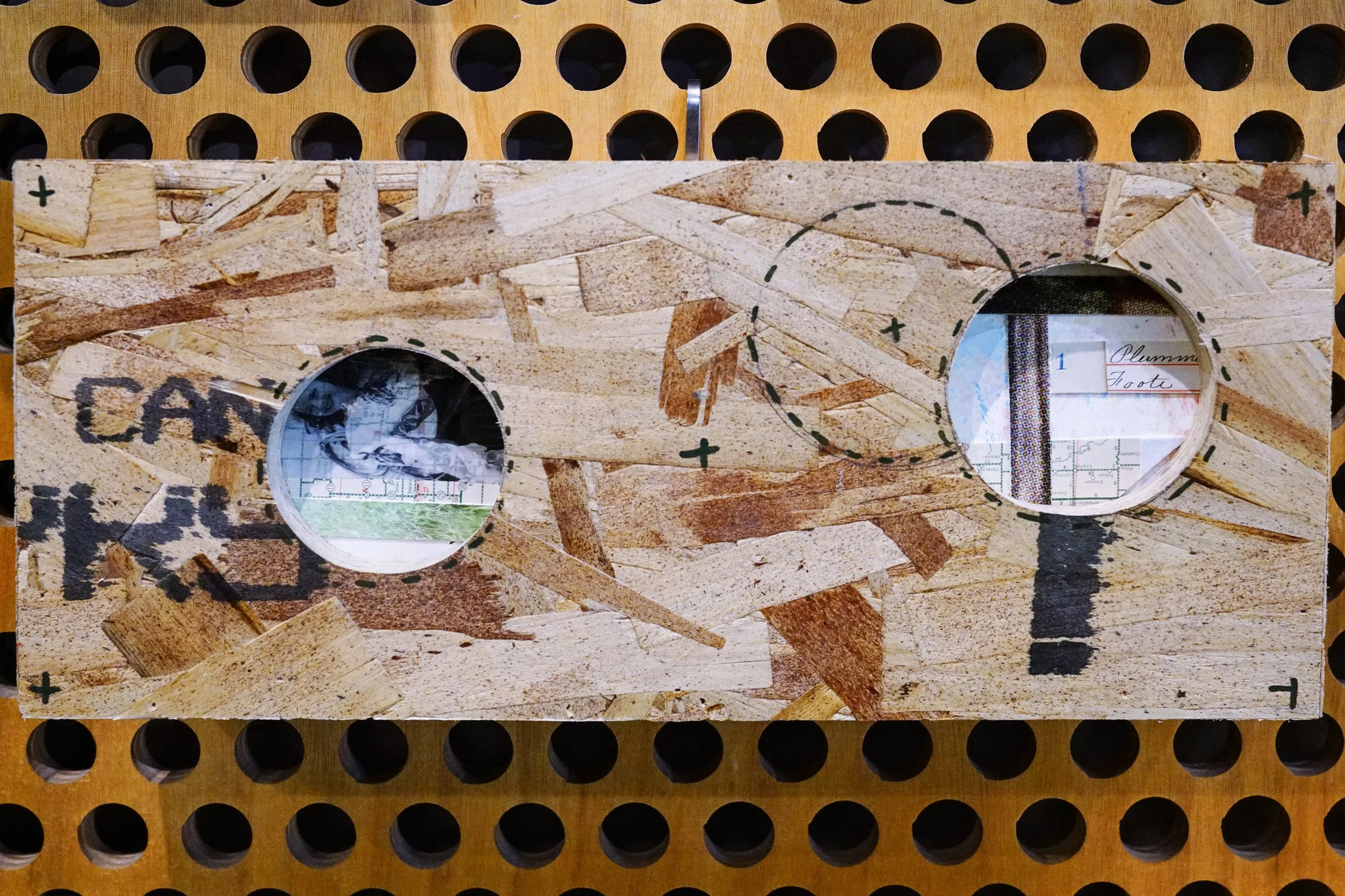 A woodworking template with two circular cutouts over a piece of particle board, with markings and an instruction to plummet the tool, set on a workbench with peg holes.