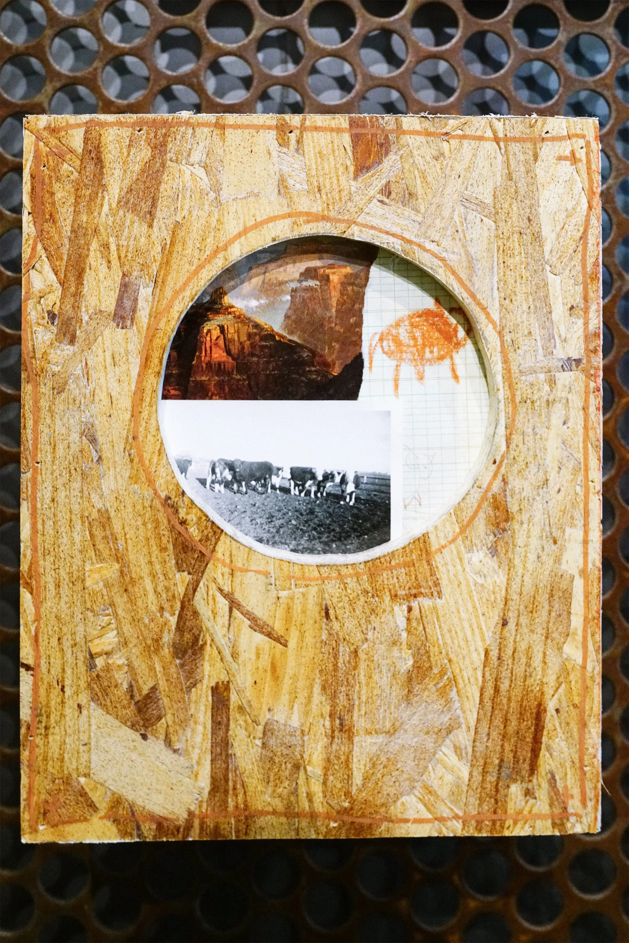 A close-up of a wooden photo frame with a circular cutout in the center, showing a vintage black-and-white photo of people, and a smaller color photo of a mountain landscape, all set on a textured, light-colored wooden surface.