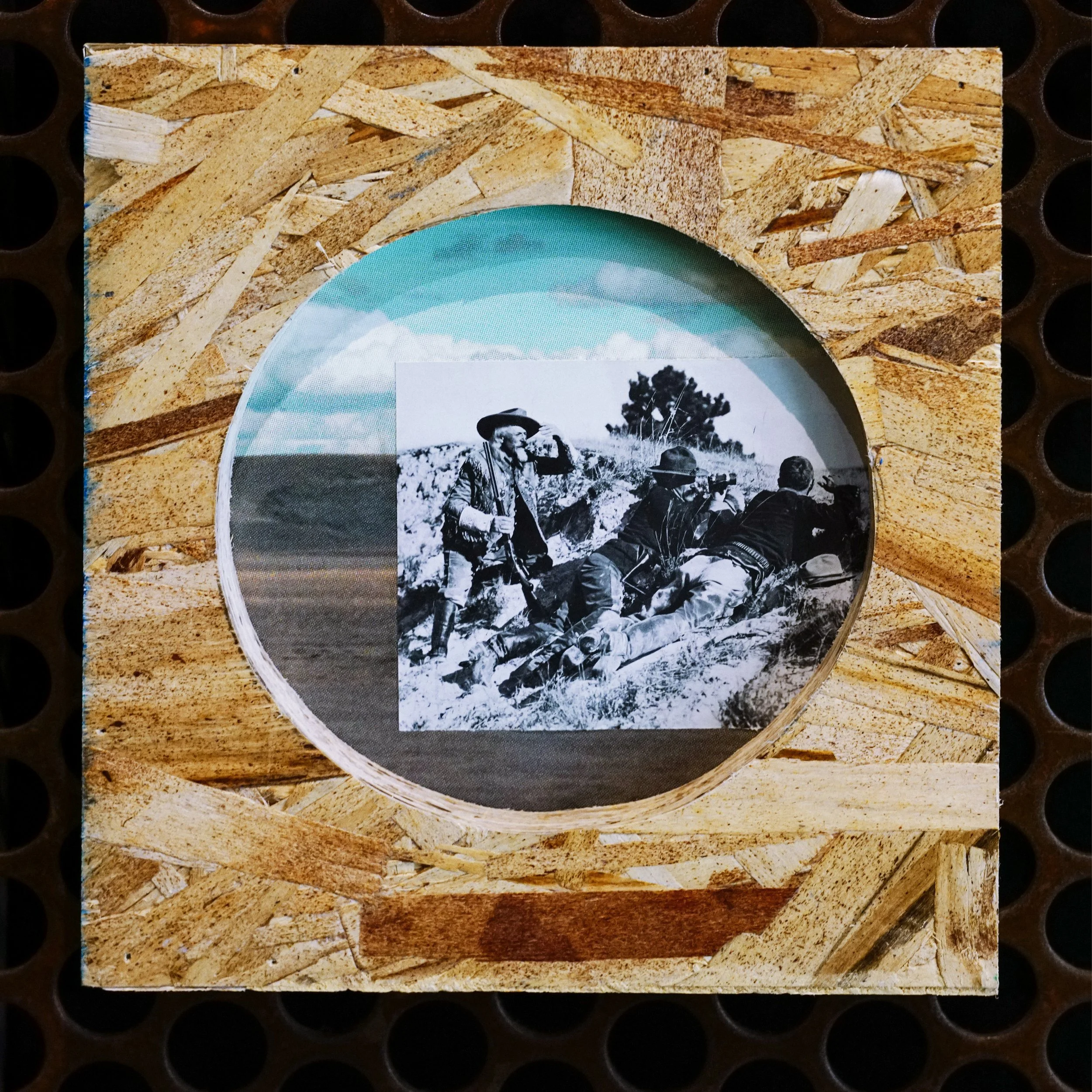 A close-up of a product package featuring a black-and-white photo of soldiers with rifles in a desert landscape, set against a background resembling a wooden or cork texture.