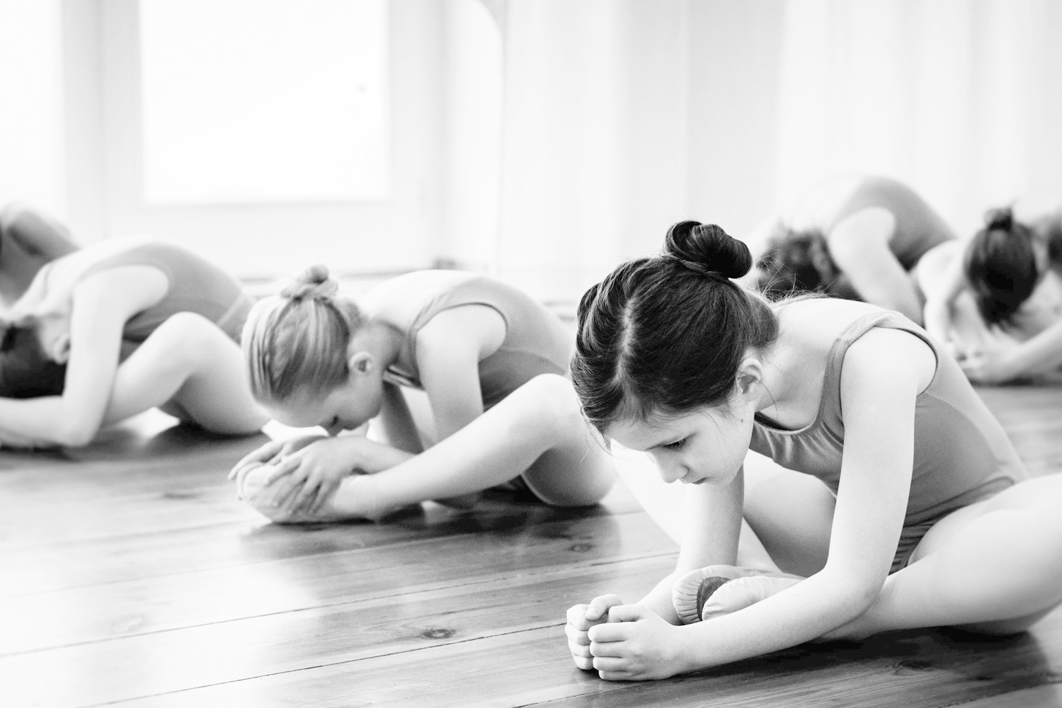 8 year-old girls in ballet uniforms stretching