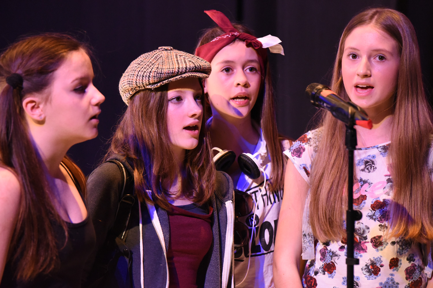 4 teenage girls singing on stage