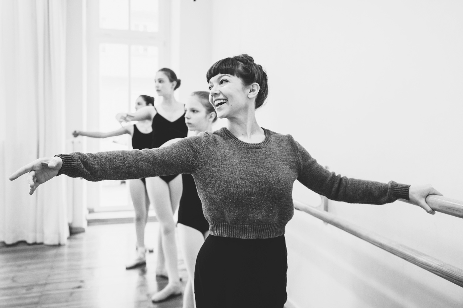 Tanzlehrerin an Ballettstange mit jungen Tänzerinnen