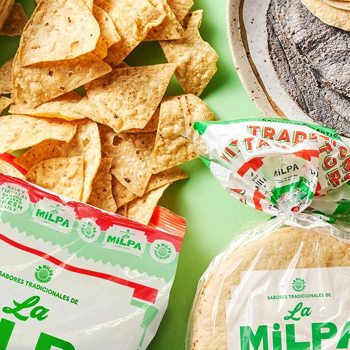 A bag of La Milpa de Rosa Nixtamal Chips spills out onto a green table (Copy)
