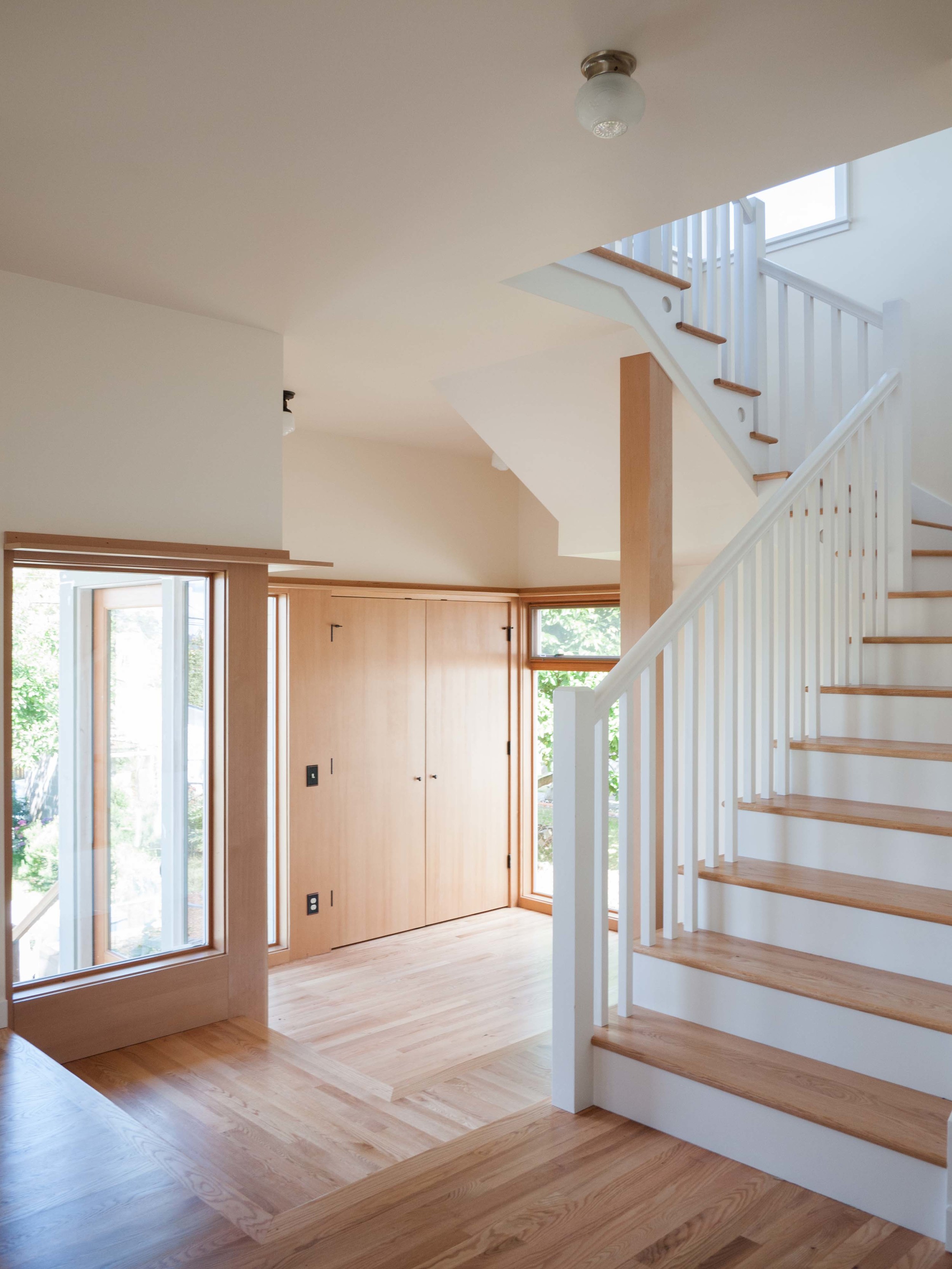 A view from the kitchen/dining area to the sunken mudroom and stairs to the second story. 