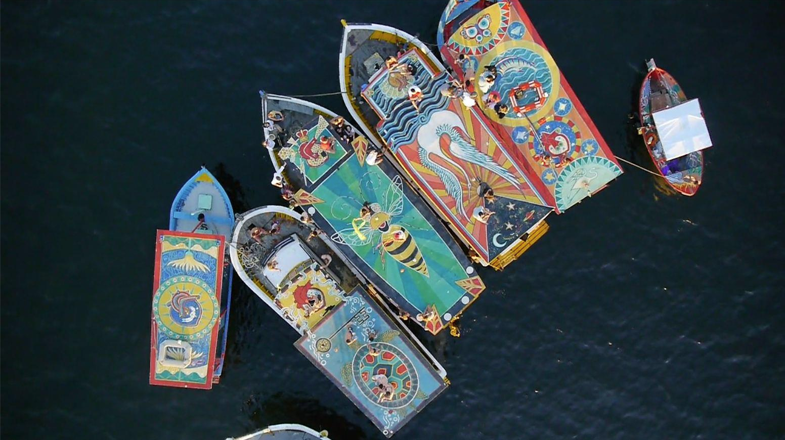   Aerial View of 6 boats at FlutuArte's closing event.    In 2012, Maxine co-created  FlutuArte , a public art installation where 45 international artists joined to paint murals on the rooftops of 60 fishing boats in a historic harbor in Rio de Janei