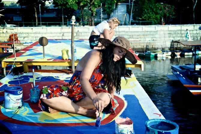   Maxine and co creator  Nicolina &nbsp;painting a mural on a boat rooftop    In 2012, Maxine co-created  FlutuArte , a public art installation where 45 international artists joined to paint murals on the rooftops of 60 fishing boats in a historic ha