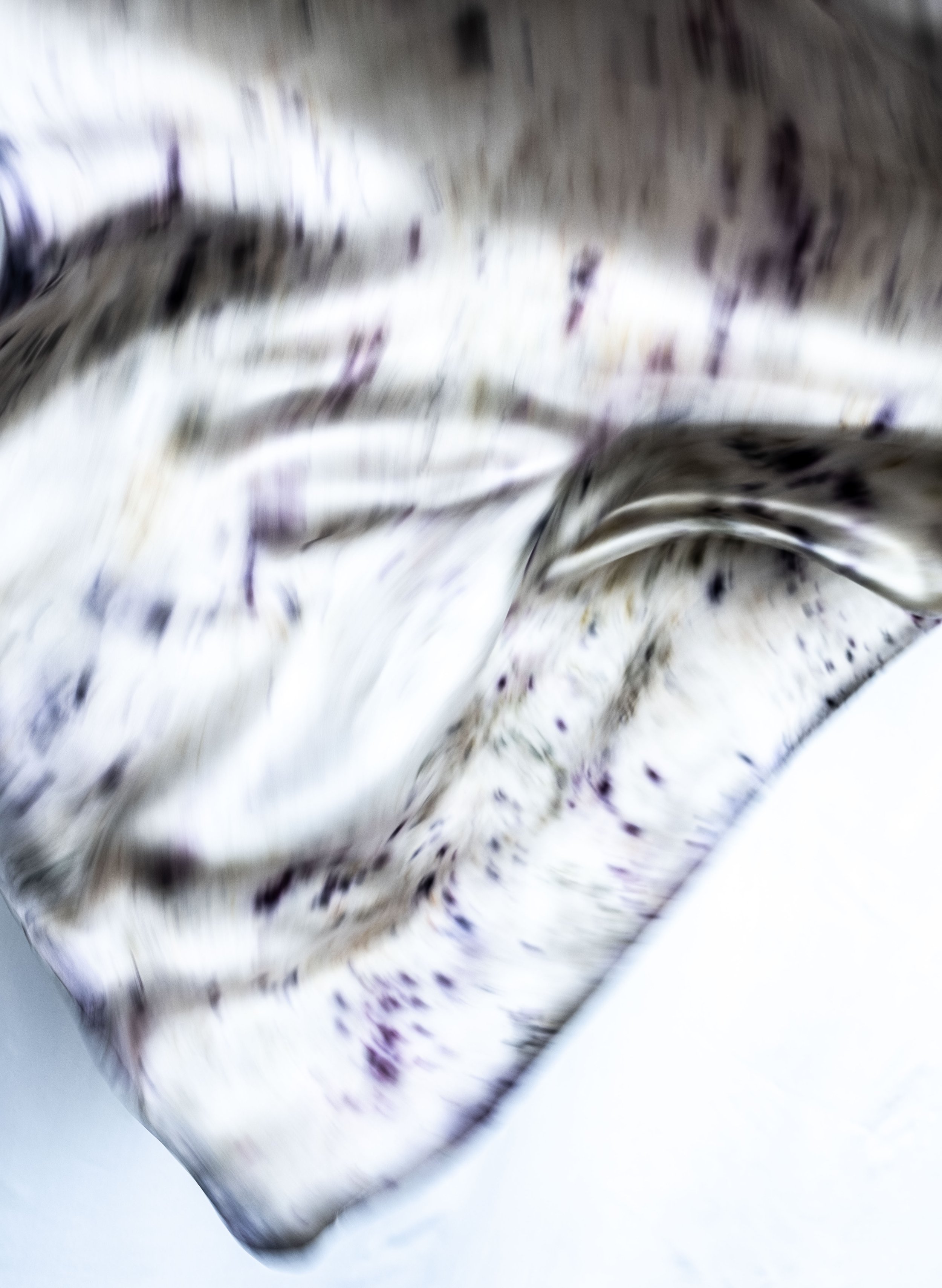 Close-up of crumpled white fabric with purple and black splatters.