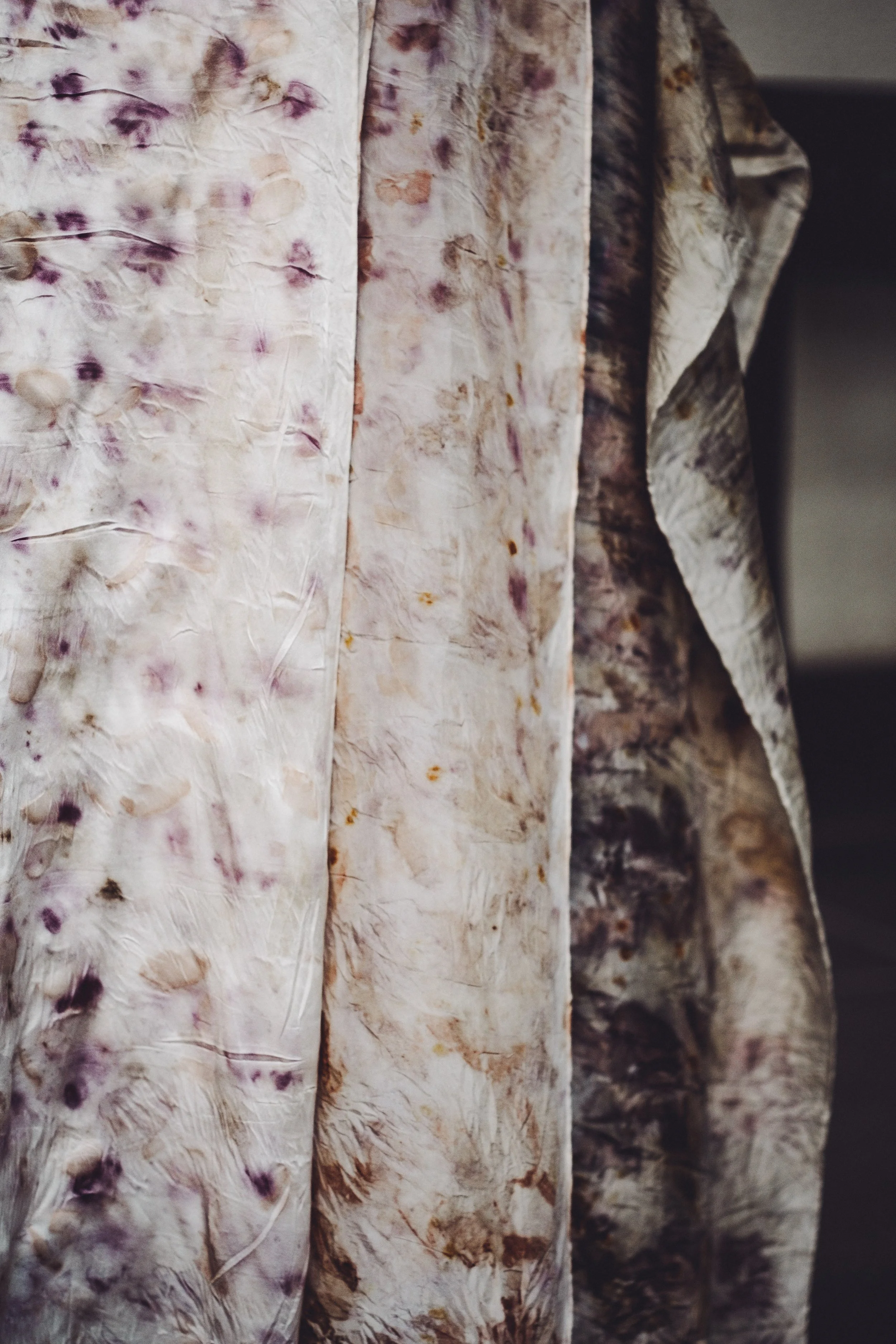 Close-up of layered patterned textiles with muted earthy tones and abstract designs.