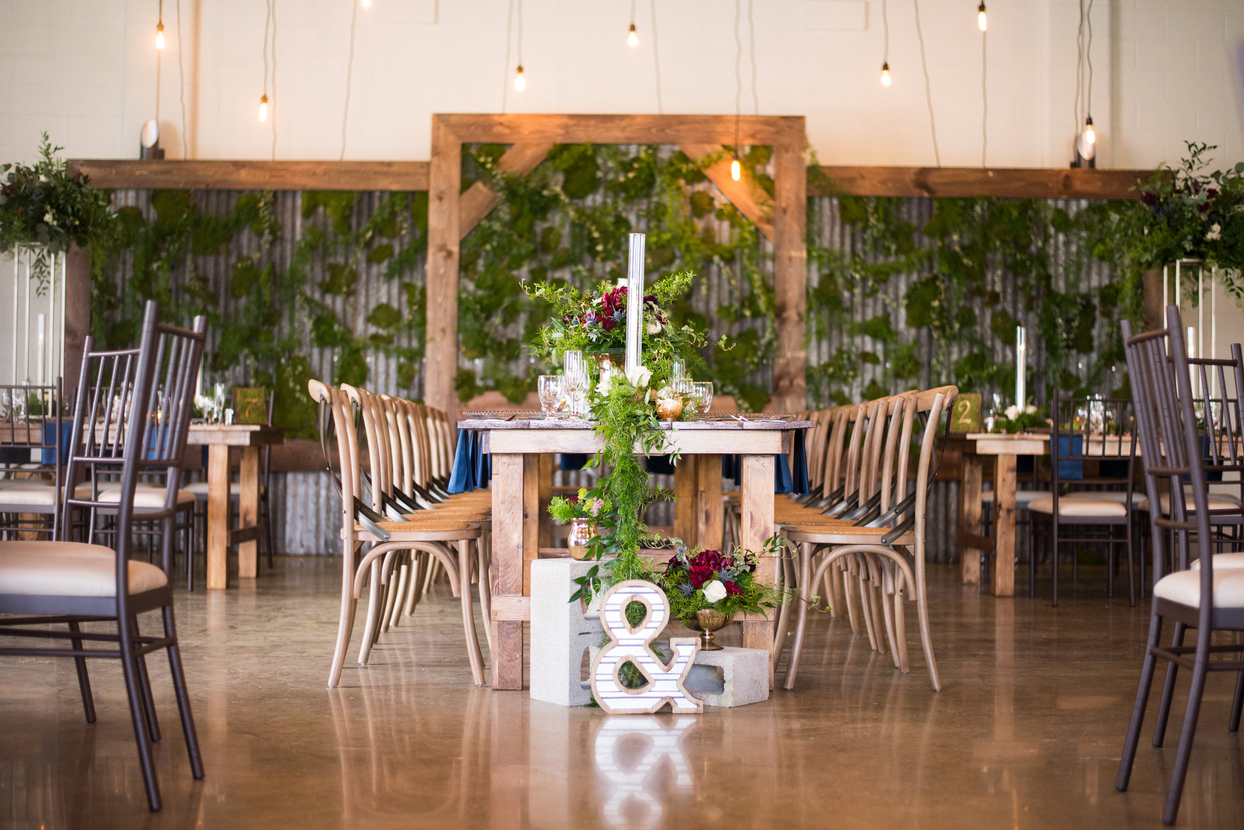 Wood harvest tables and vineyard chairs are always a beautiful choice for a Head Table, especially when they're setup king's style and feature a greenery garland. Venue: St. Marys Golf & Country Club . Decor & Styling: Above & Beyond Event Design . Floral Design: Lyric Flowers .