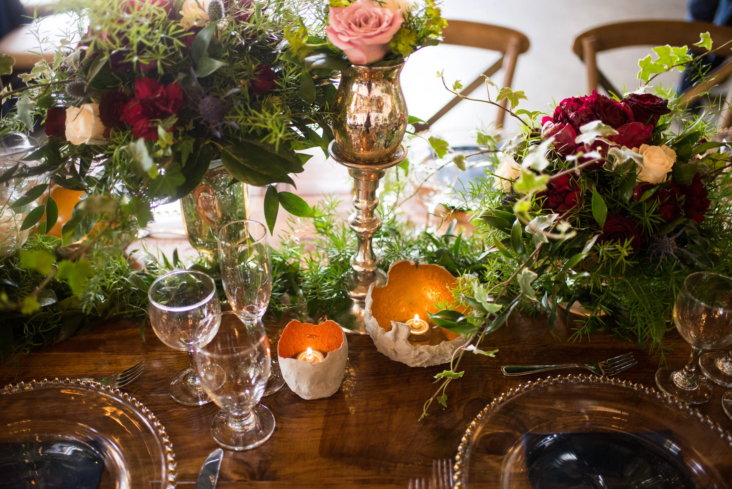 Custom-made cement candleholders with copper-toned interiors, by Lyric Flowers , reflect romantic warm light for a wedding reception.