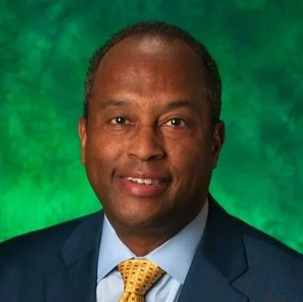 A man in a suit and tie with a green textured background.