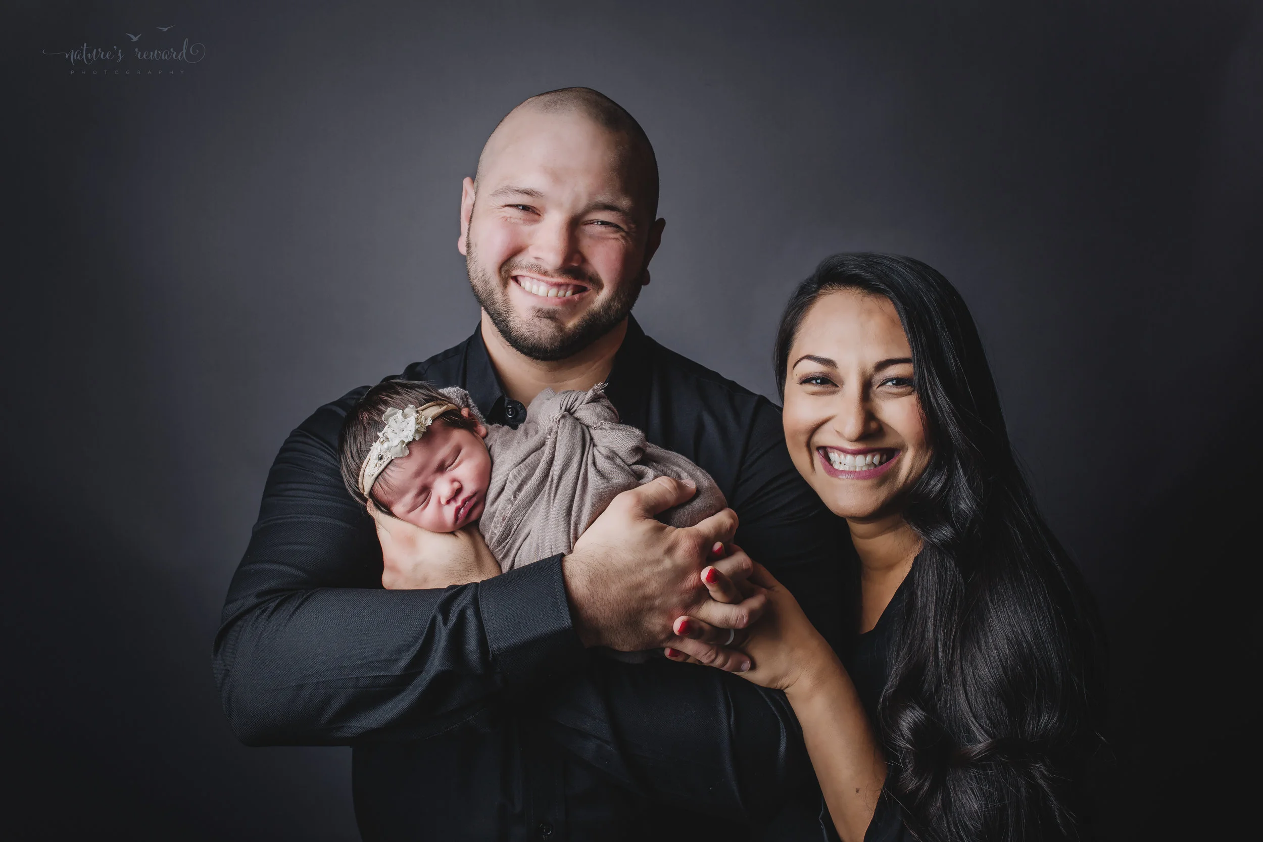 Newborn baby girl and her parents in the family portrait by Nature’s Reward Photography