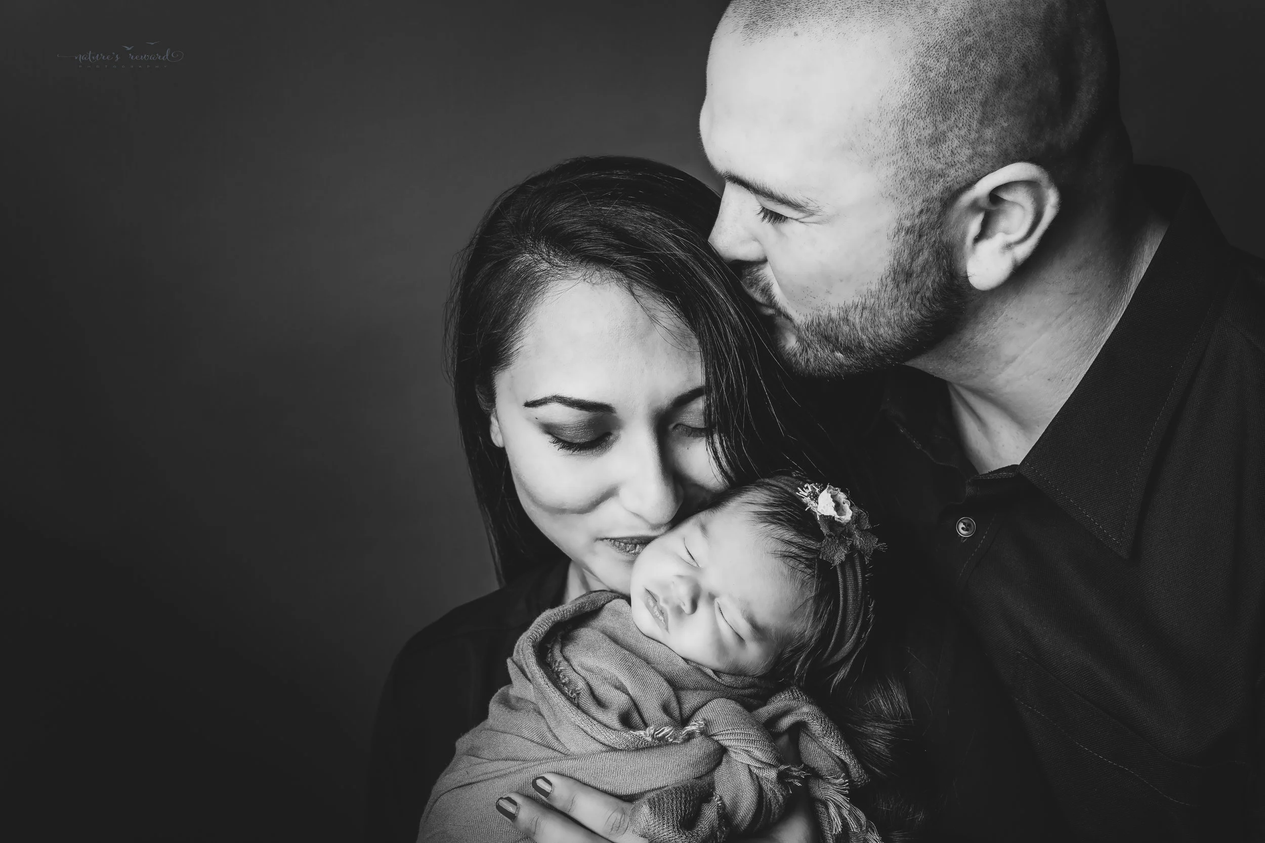 Newborn baby girl and her parents in the black and white family portrait by Nature’s Reward Photography