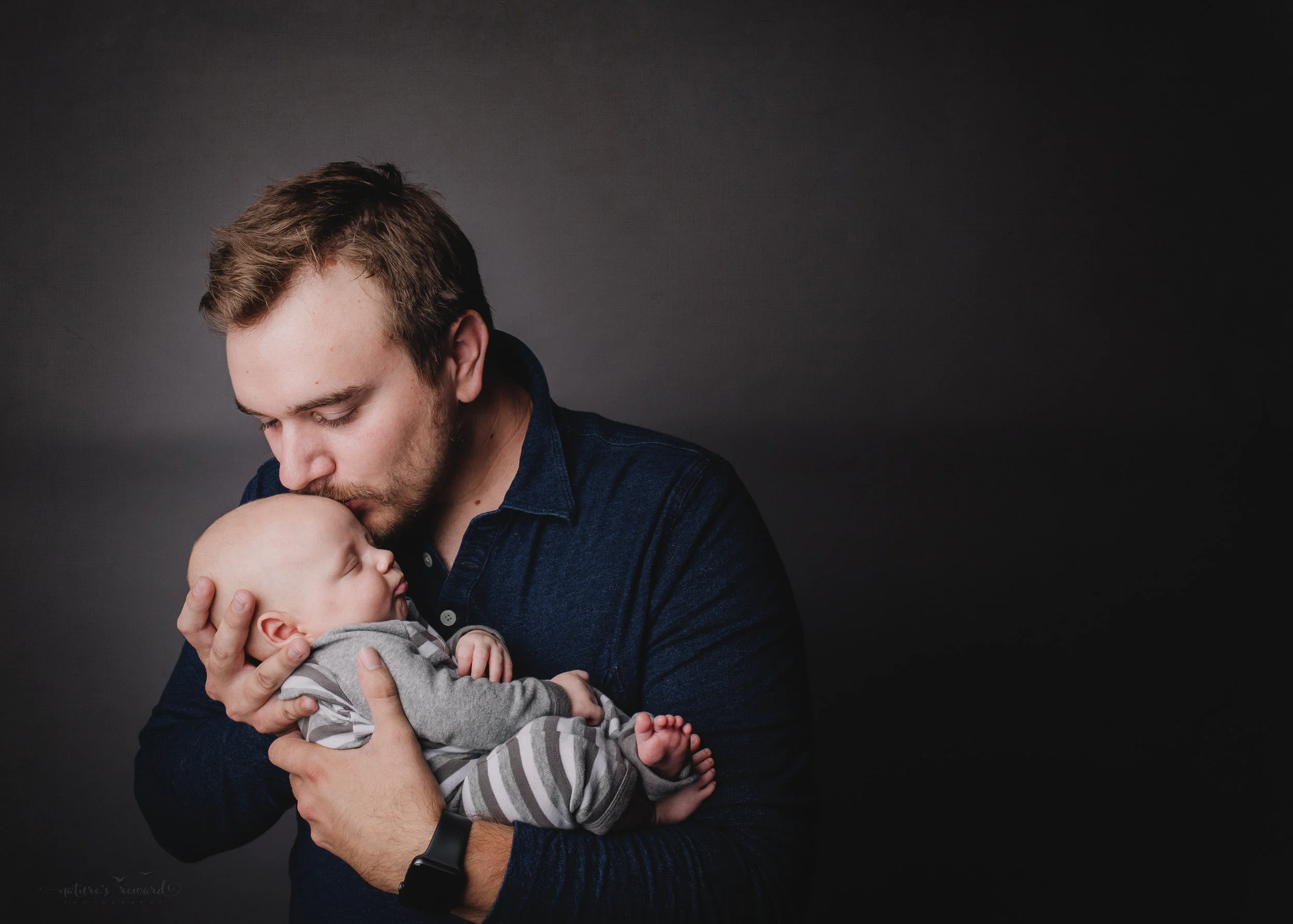 2 month old newborn baby boy being held by his loving father- a portrait by nature’s Reward Photography