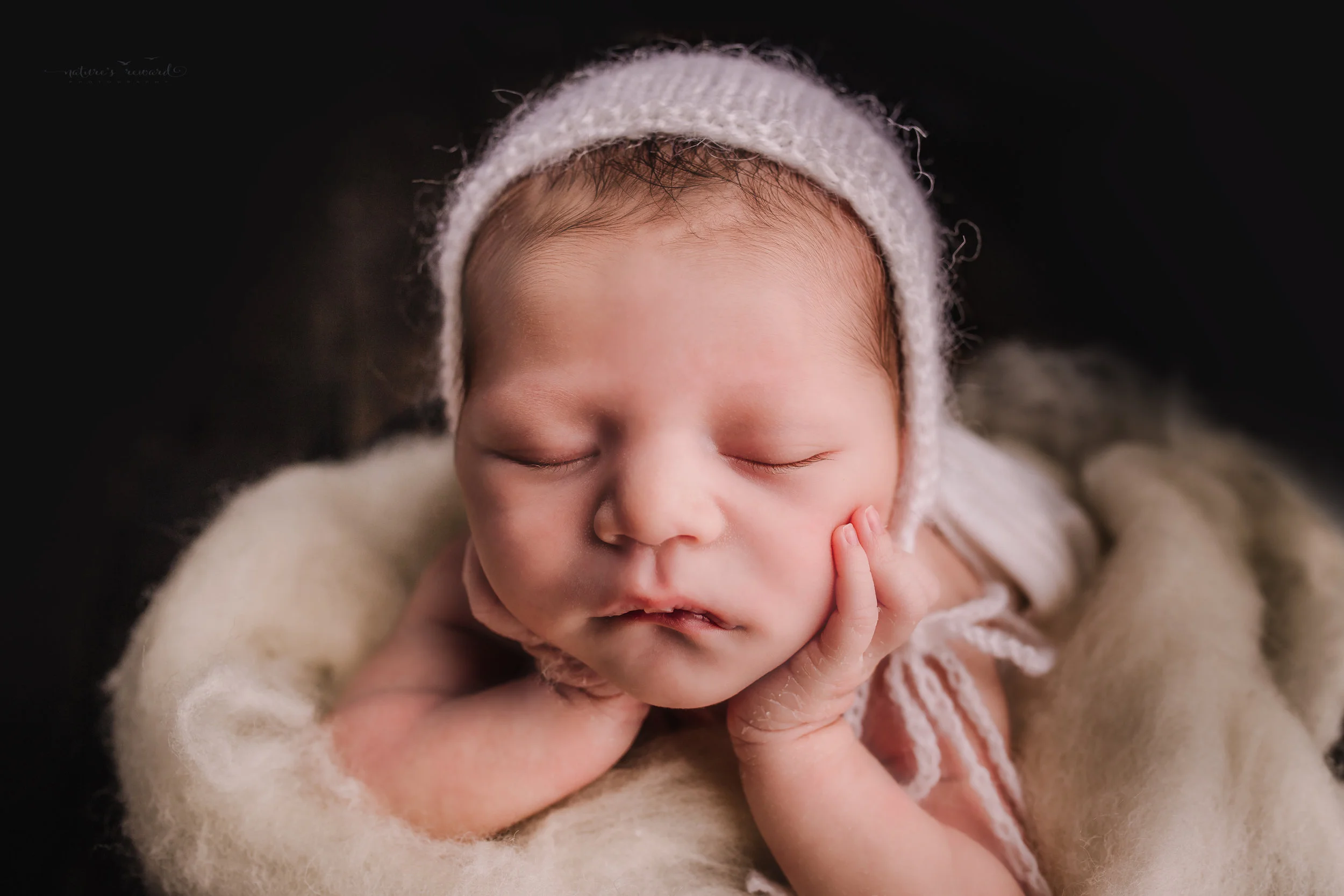 Newborn baby boy swaddled in white in bucket of white fluff on a dark wood floor by san Bernardino’s maternity, newborn and family photography, Nature’s Reward Photography