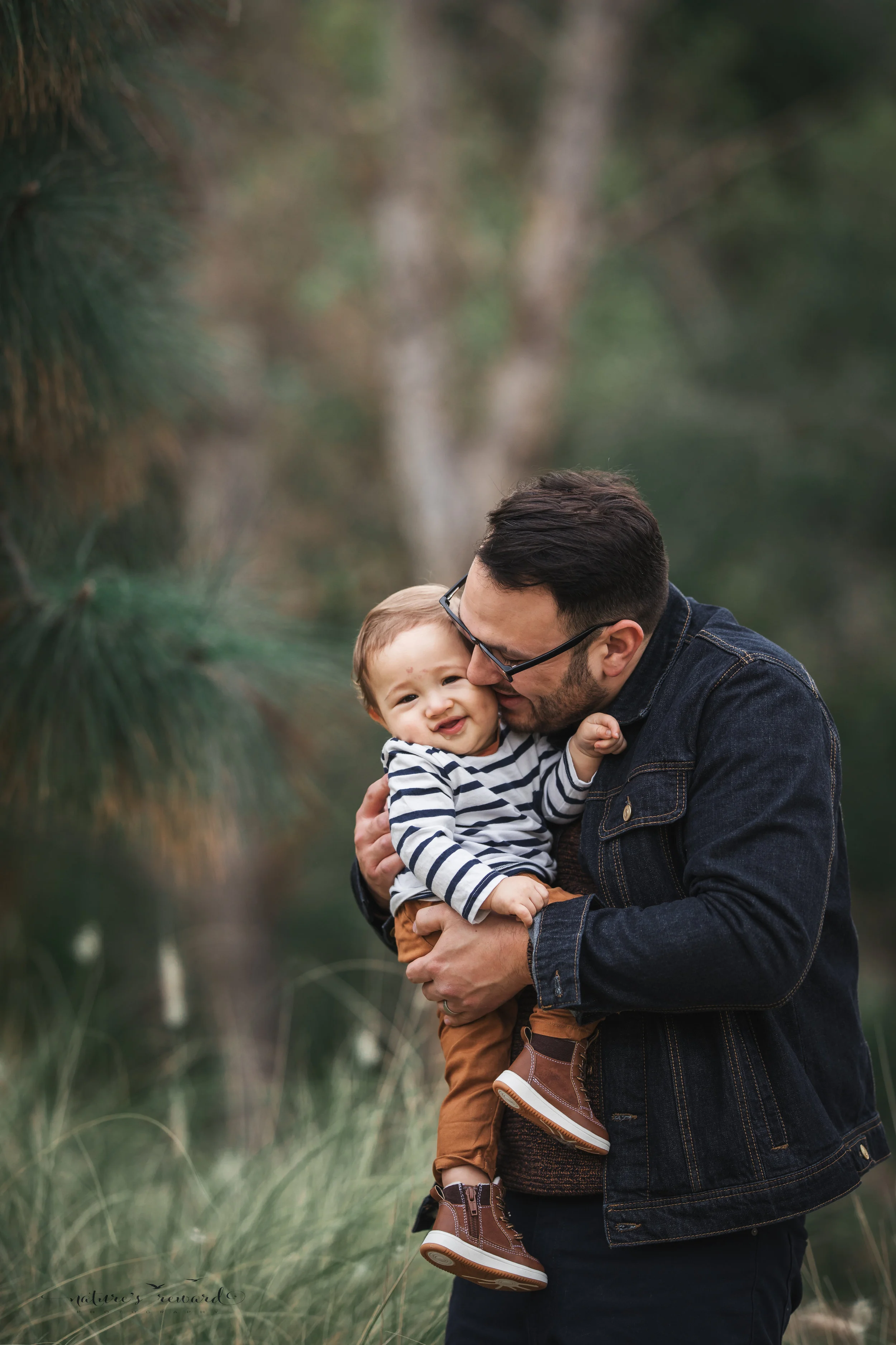 Baby boy in tans and blues with his father in a portrait by Nature’s reward Photography
