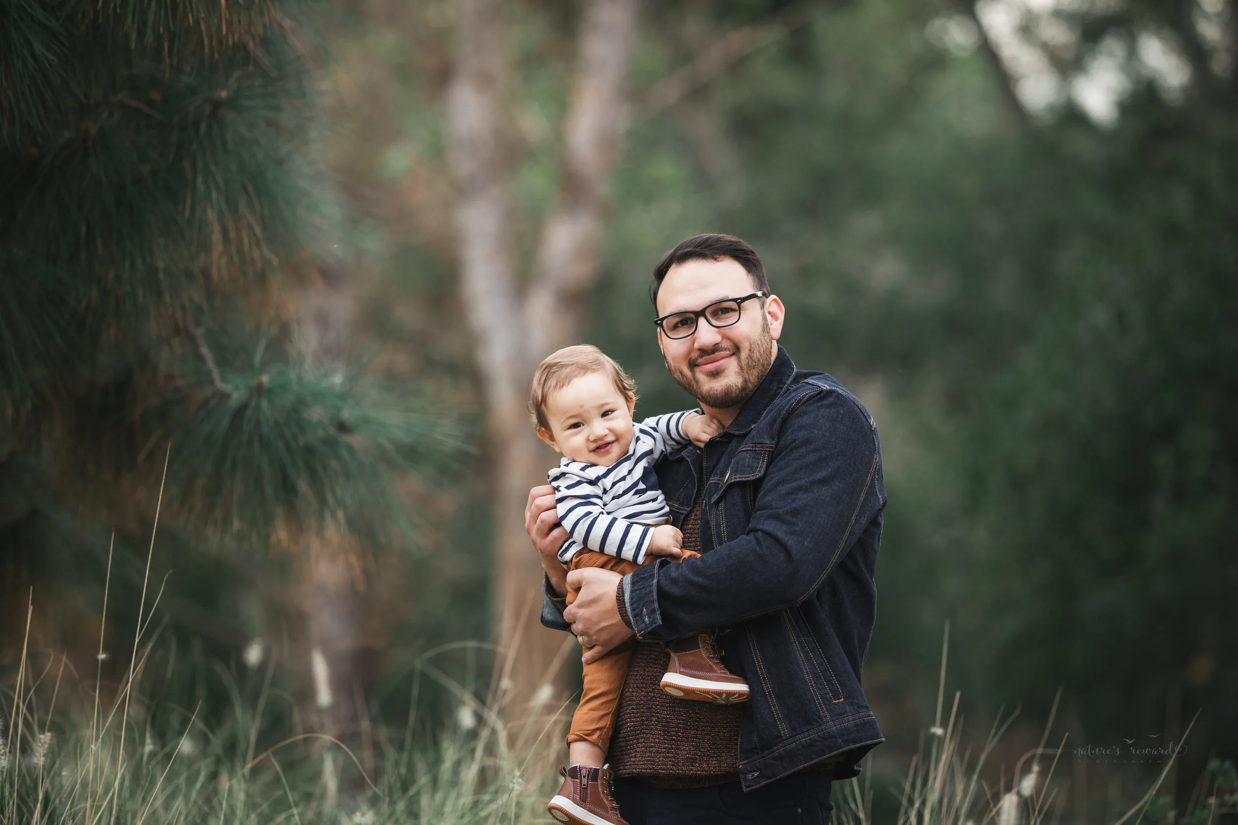 Baby boy in tans and blues with his father in a portrait by Nature’s reward Photography