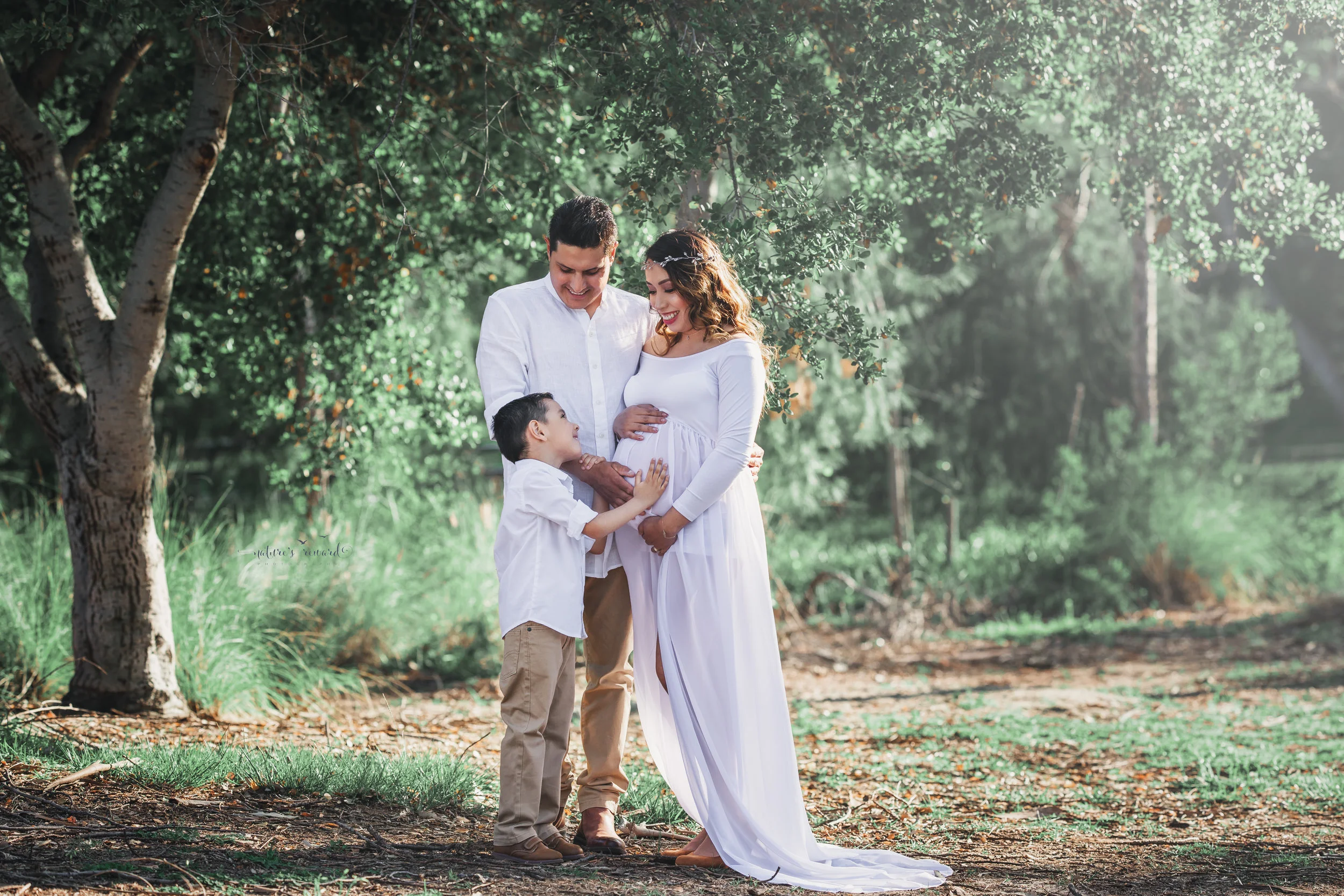 Expecting mother to be in white open front gown in this family maternity session portrait by Nature’s Reward Photography