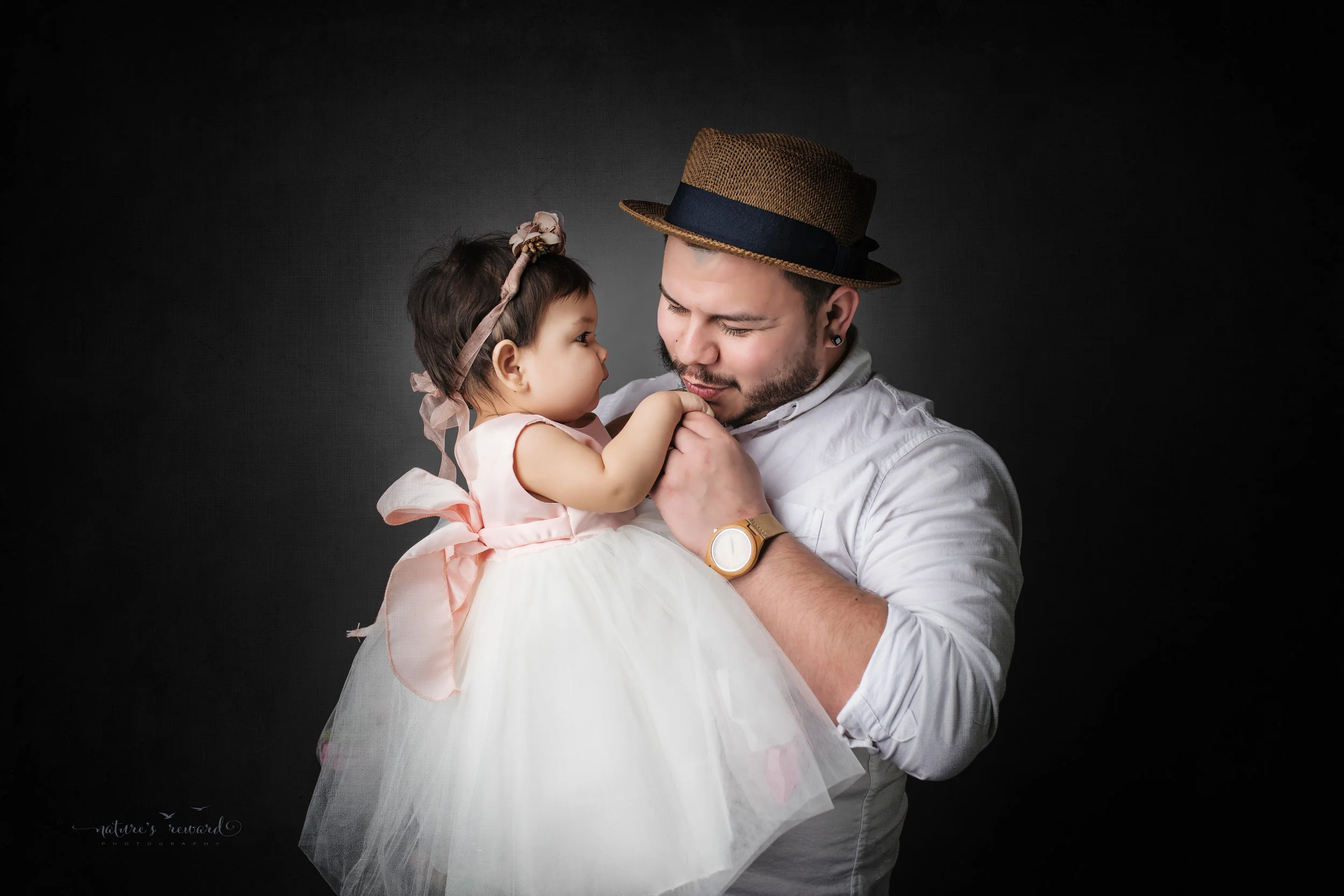 Father and daughter dressed in white on a grey background, a portrait by Nature’s Reward Photography