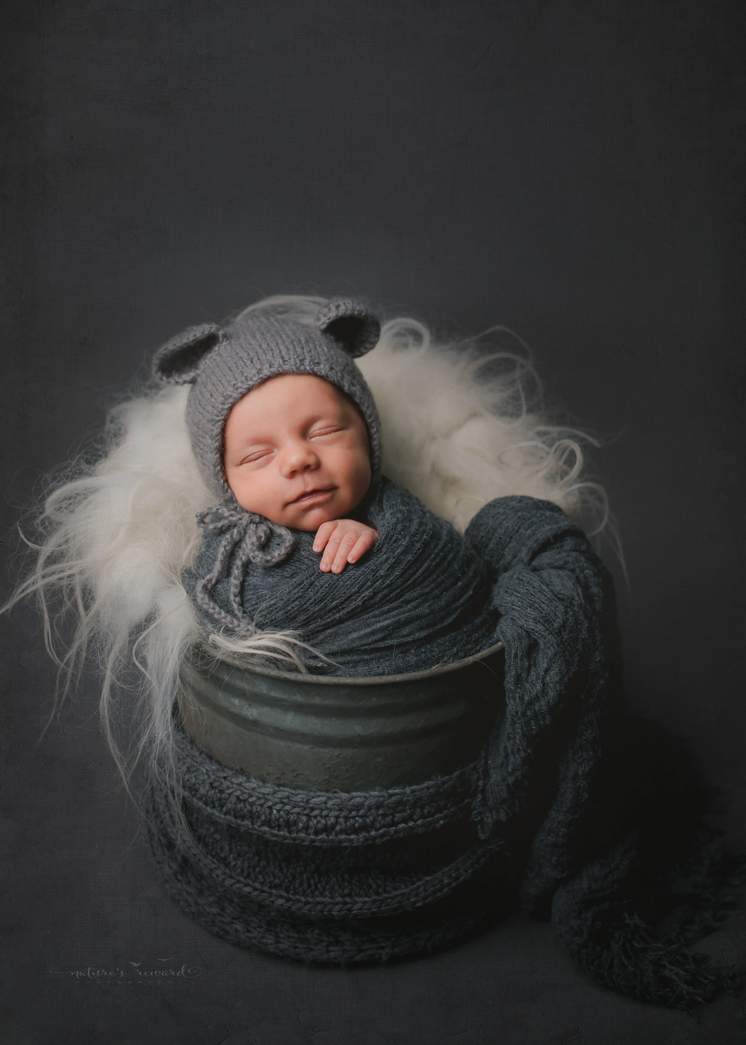A baby boy in a bucket wearing a bear bonnet - a portrait by Nature's Reward Photography