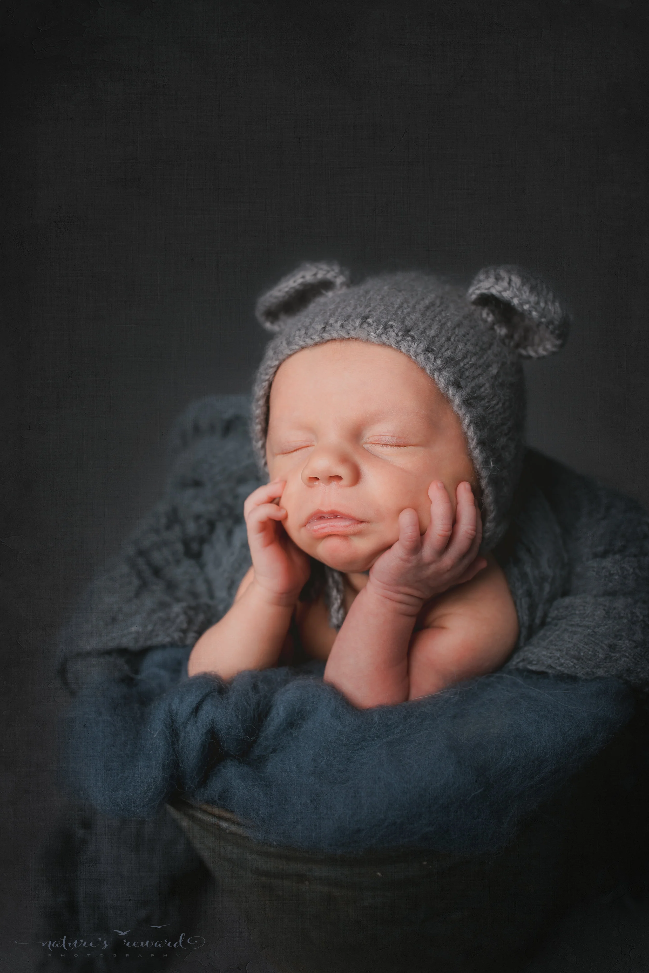 A baby boy in a bucket wearing a bear bonnet - a portrait by Nature's Reward Photography