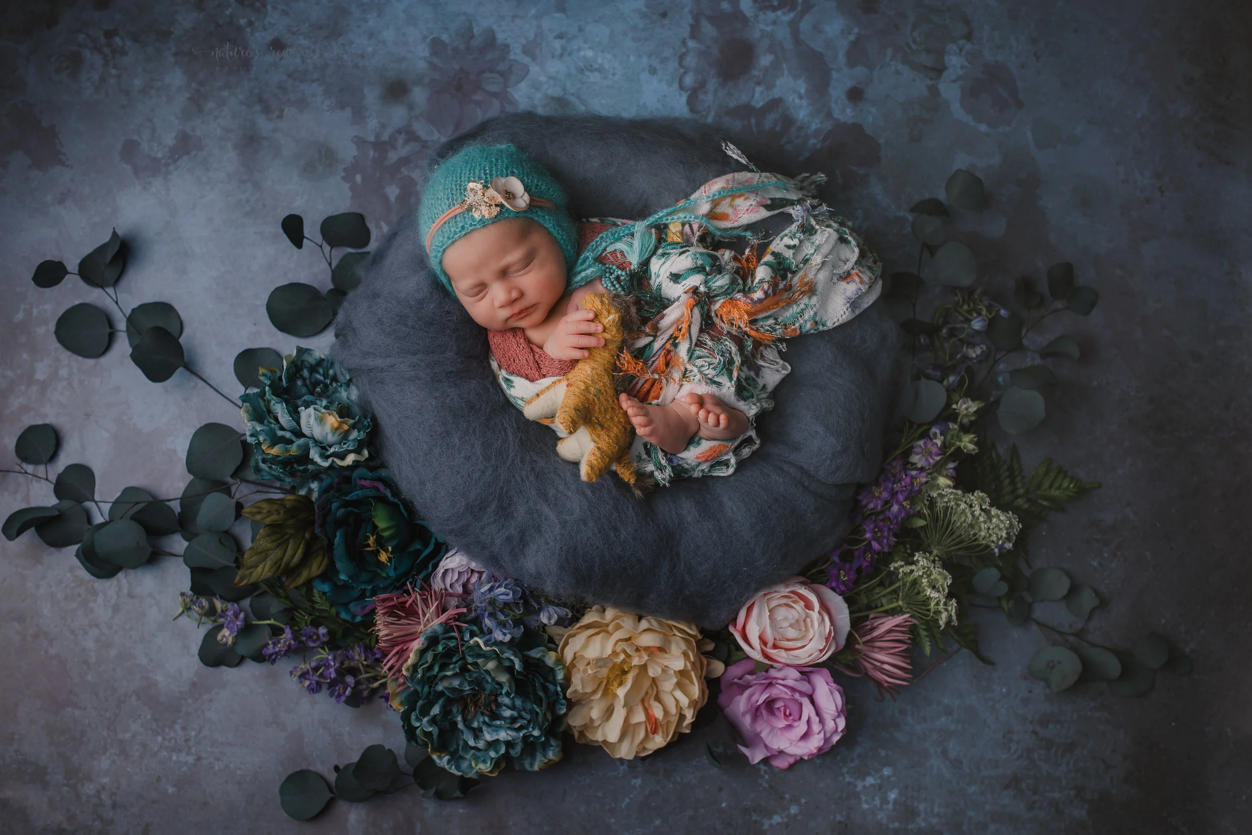 2 week old newborn baby girl in blue and teal with pops of pink and orange.