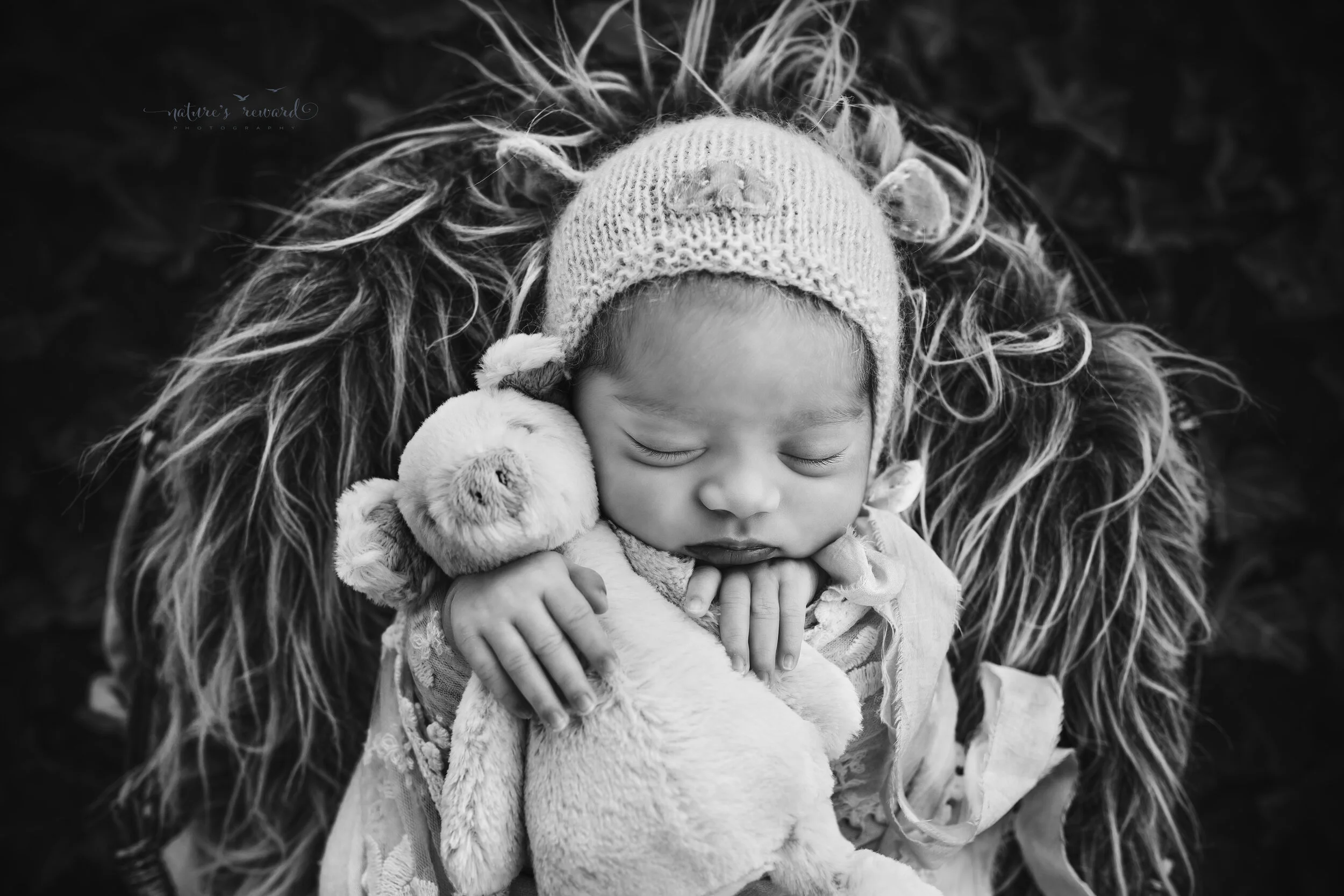 Black and White portrait of a baby girl swaddled in wearing a pig bonnet (the year of the pig) in a garden of ivy, a newborn portrait by Nature’s Reward Photography