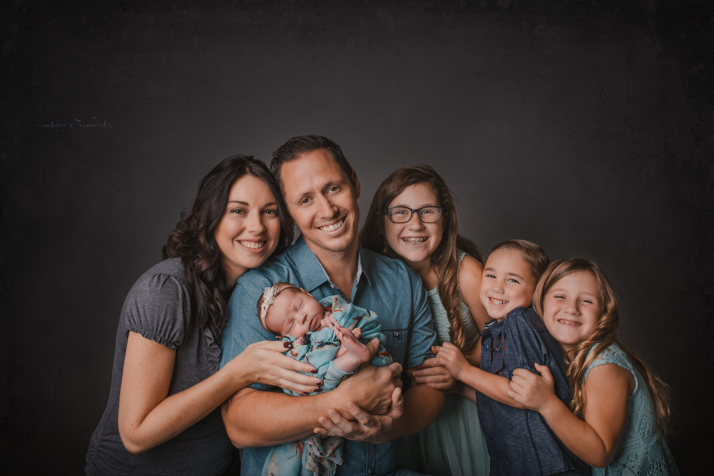 Newborn Baby girl in a family portrait by Nature’s Reward Photography
